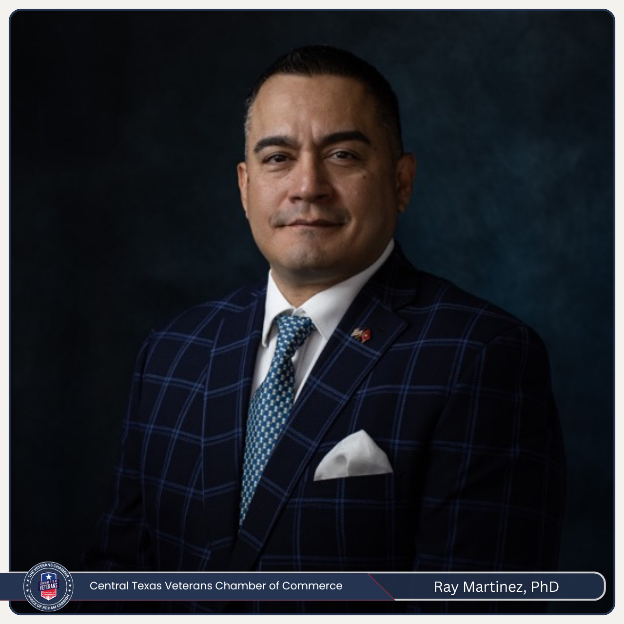 A man in a suit and tie is standing in front of a blue background.