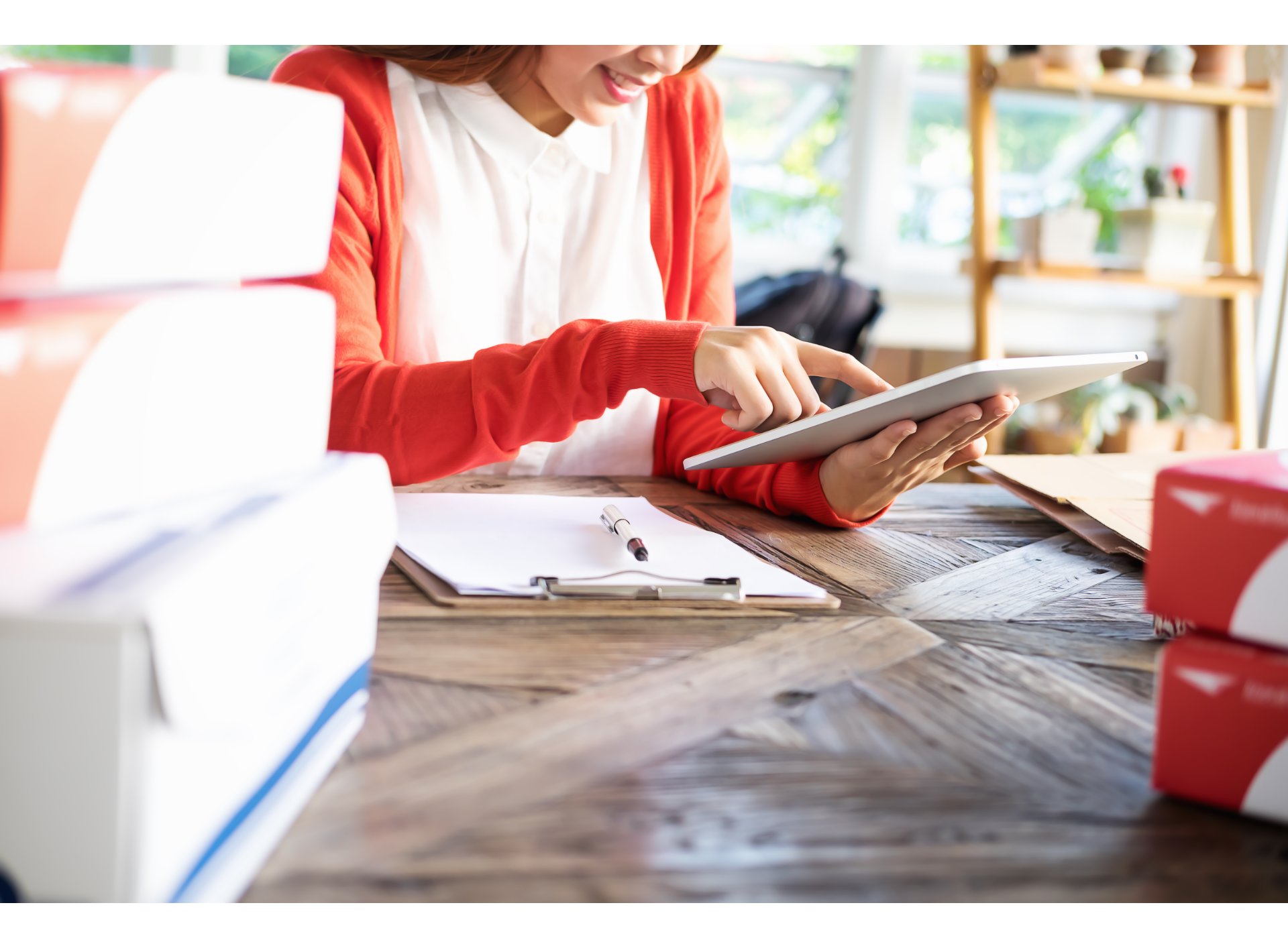 A woman is sitting at a table using a tablet computer.