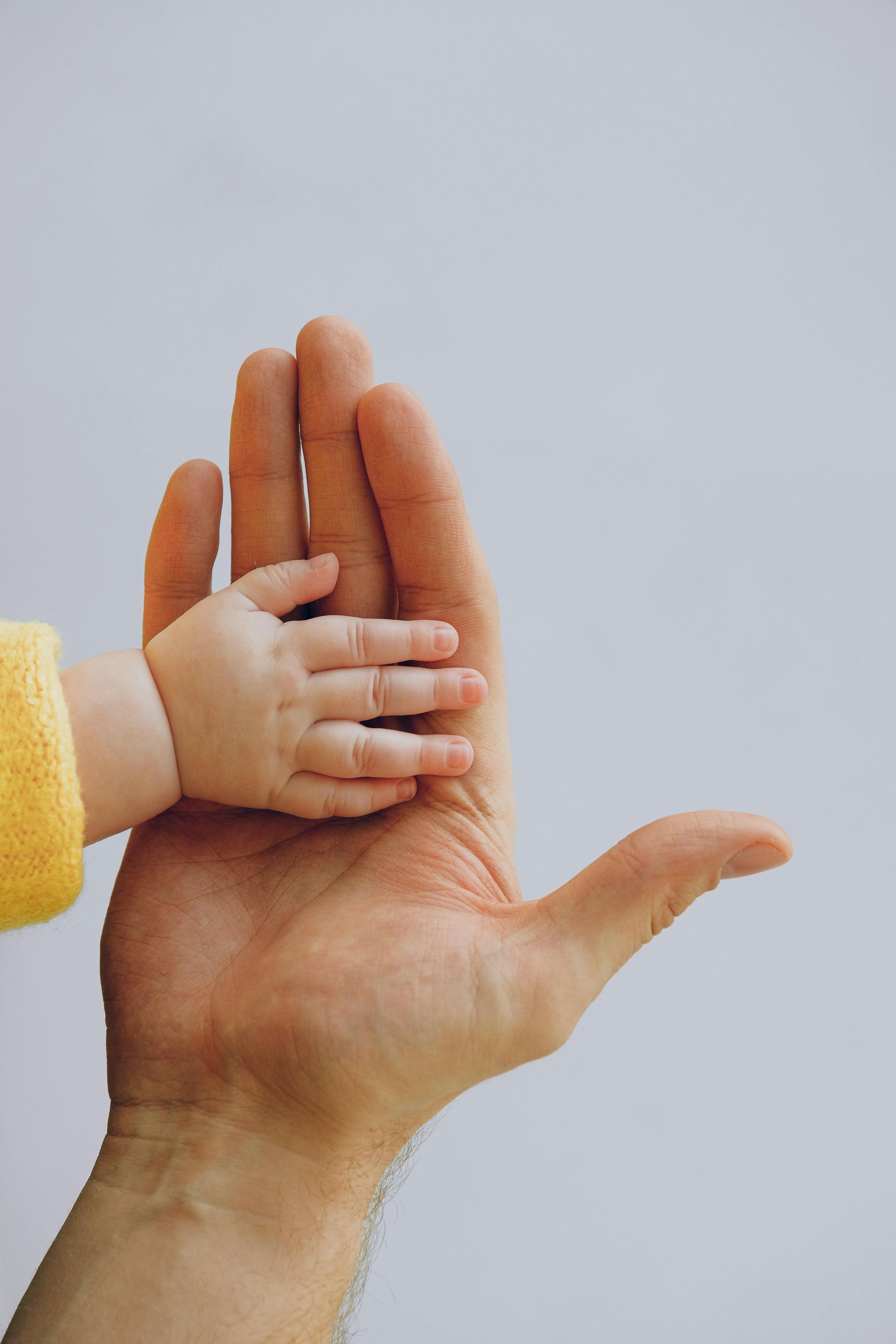 A man is holding a baby 's hand in his palm.