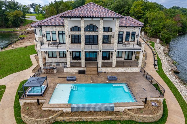 An aerial view of a large house with a swimming pool in front of it.