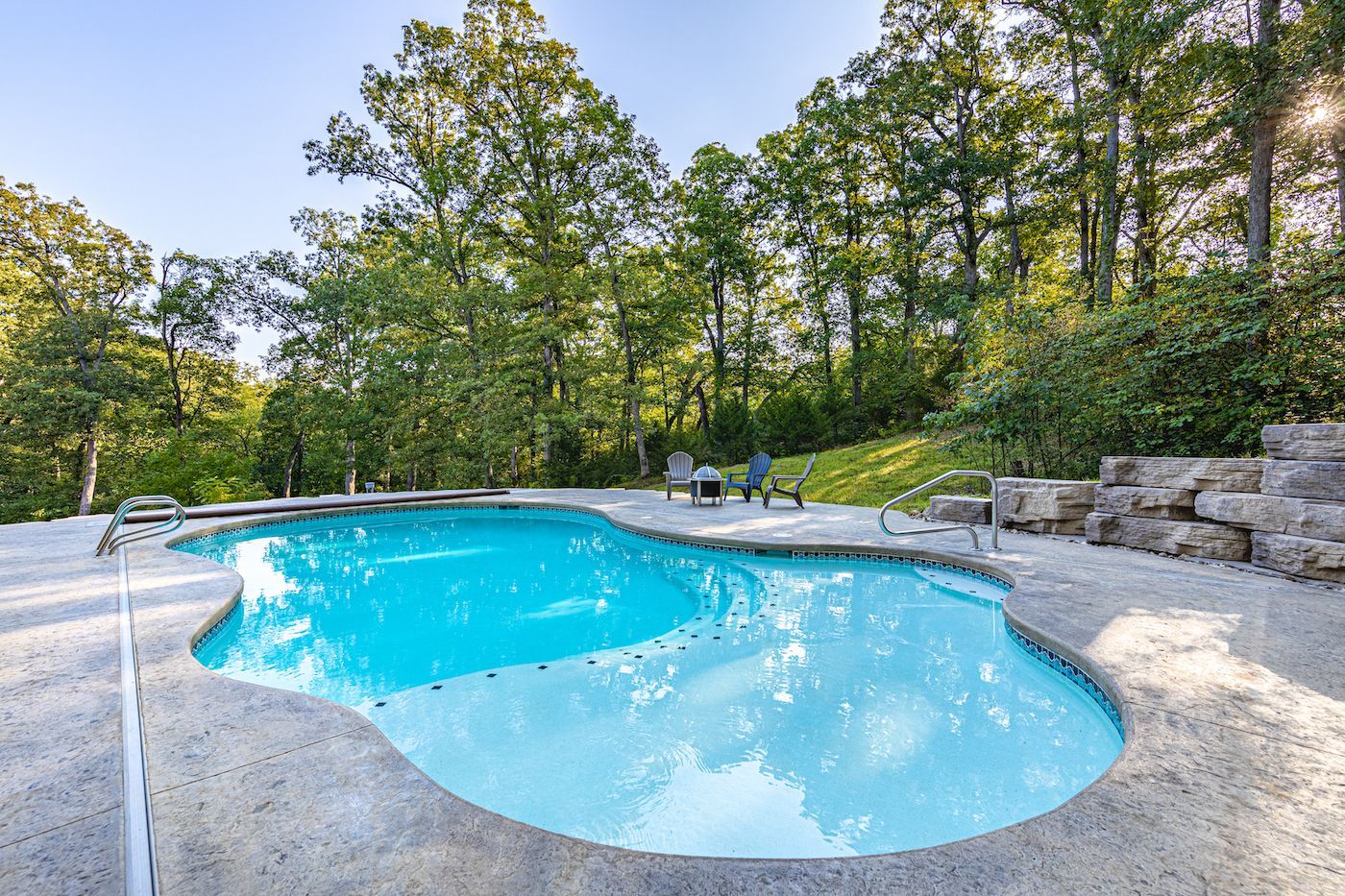 An Organically Shaped Pool Surrounded by Trees. Build a Pool in Your Backyard in Jefferson City, MO.