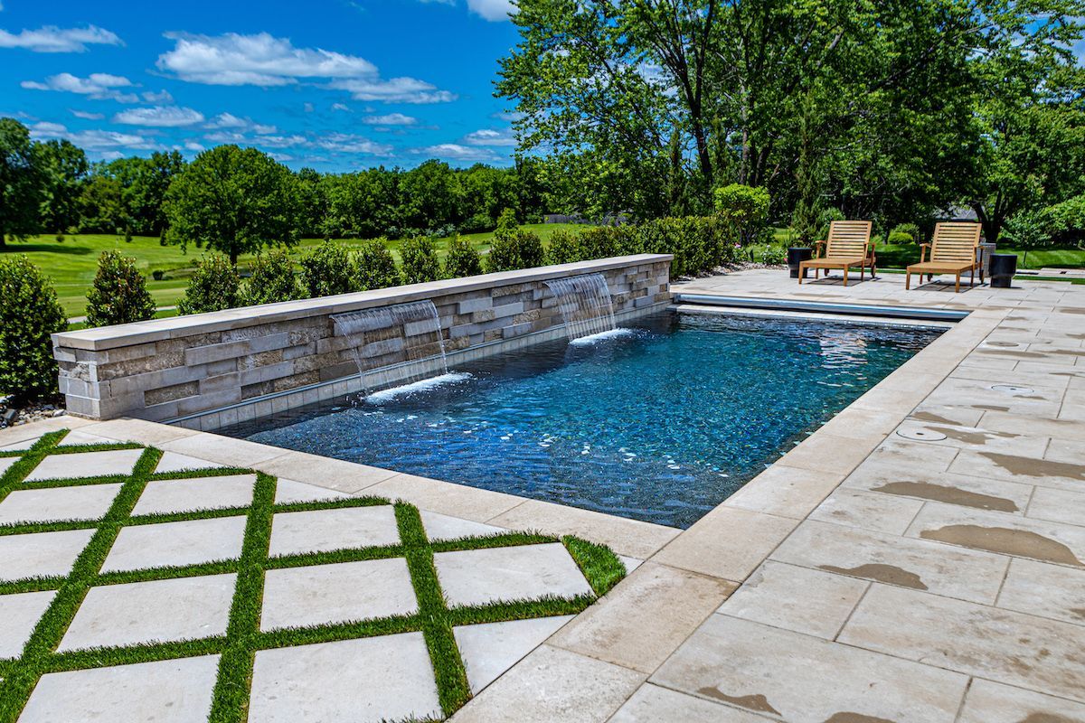 An aerial view of a large swimming pool in front of a house.