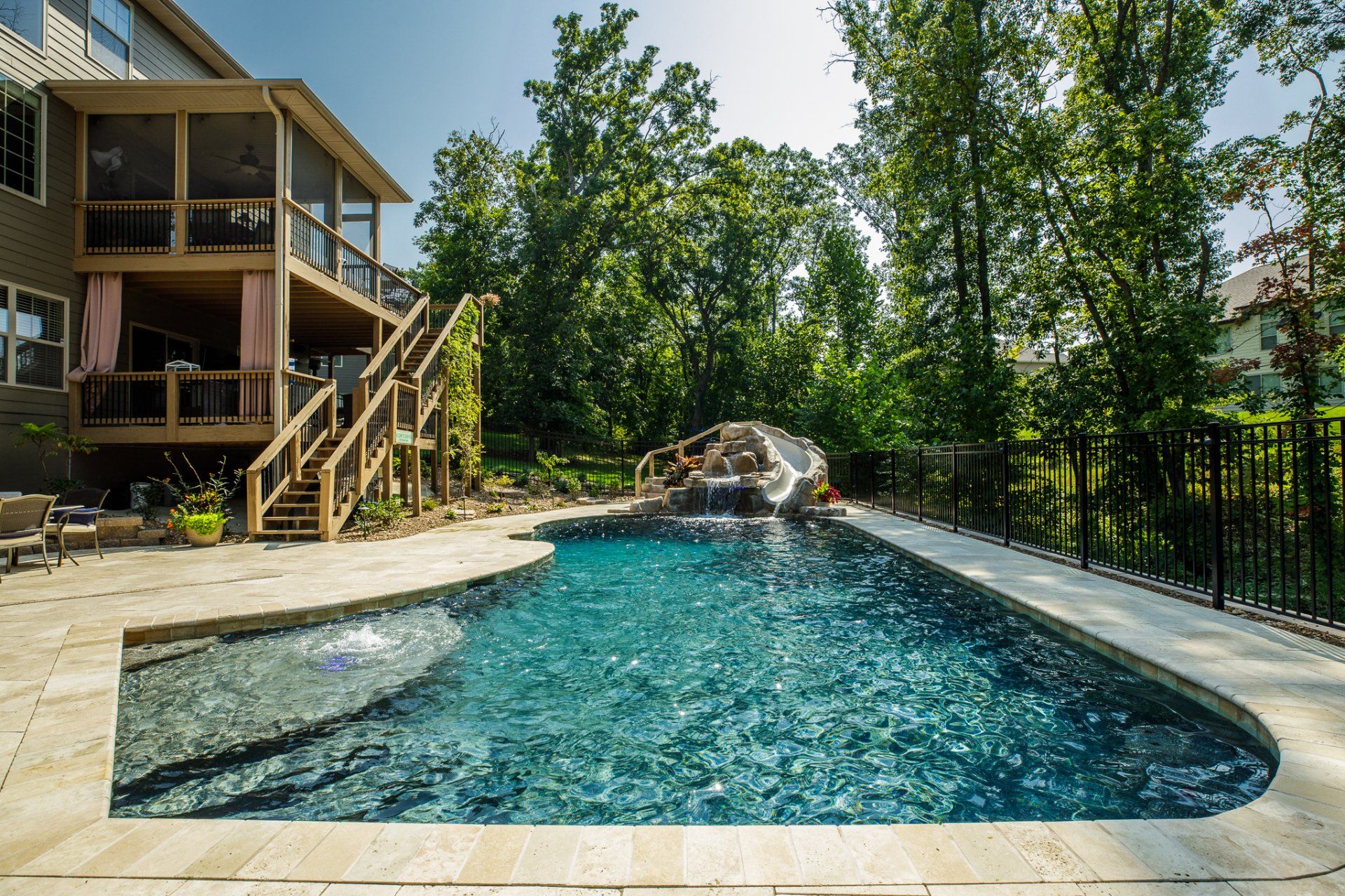 There is a large swimming pool in the backyard of a house.