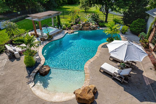 An aerial view of a large swimming pool surrounded by chairs and umbrellas.