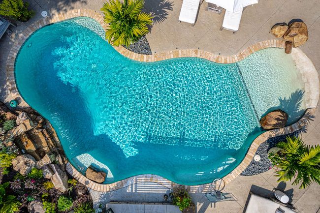 An aerial view of a large swimming pool surrounded by trees and chairs.