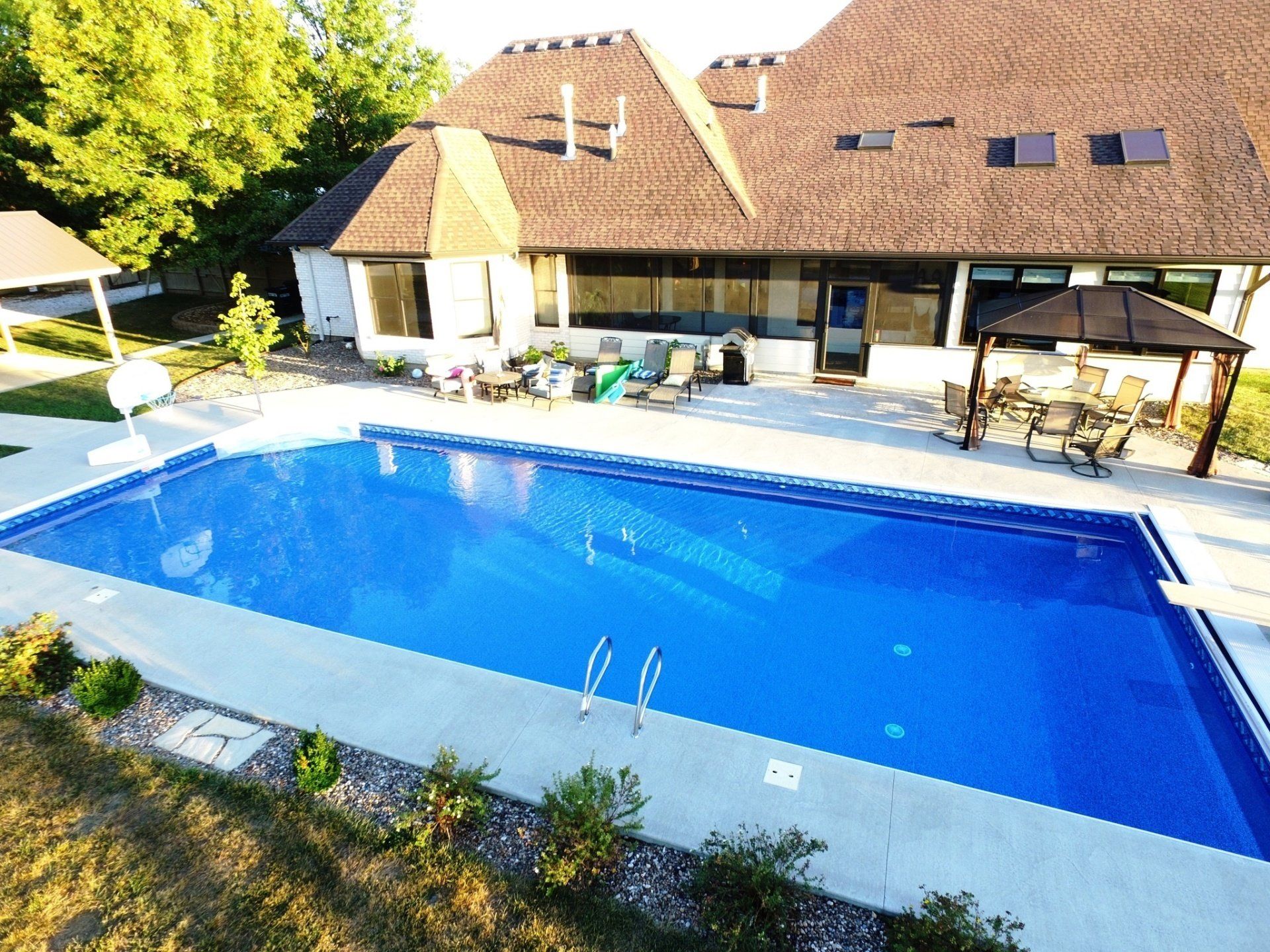 An aerial view of a large swimming pool in front of a house