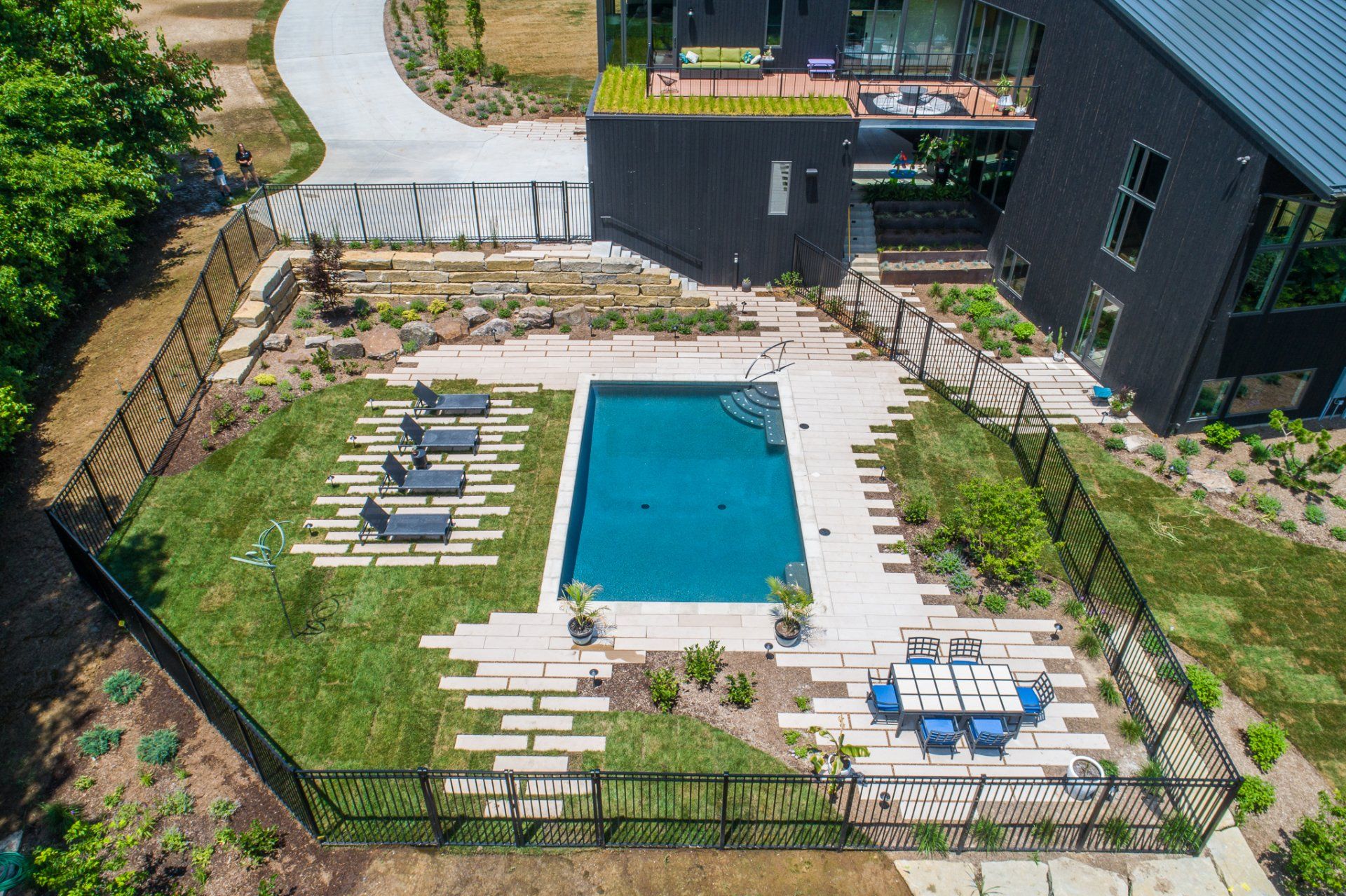 An aerial view of a large swimming pool in the backyard of a house.