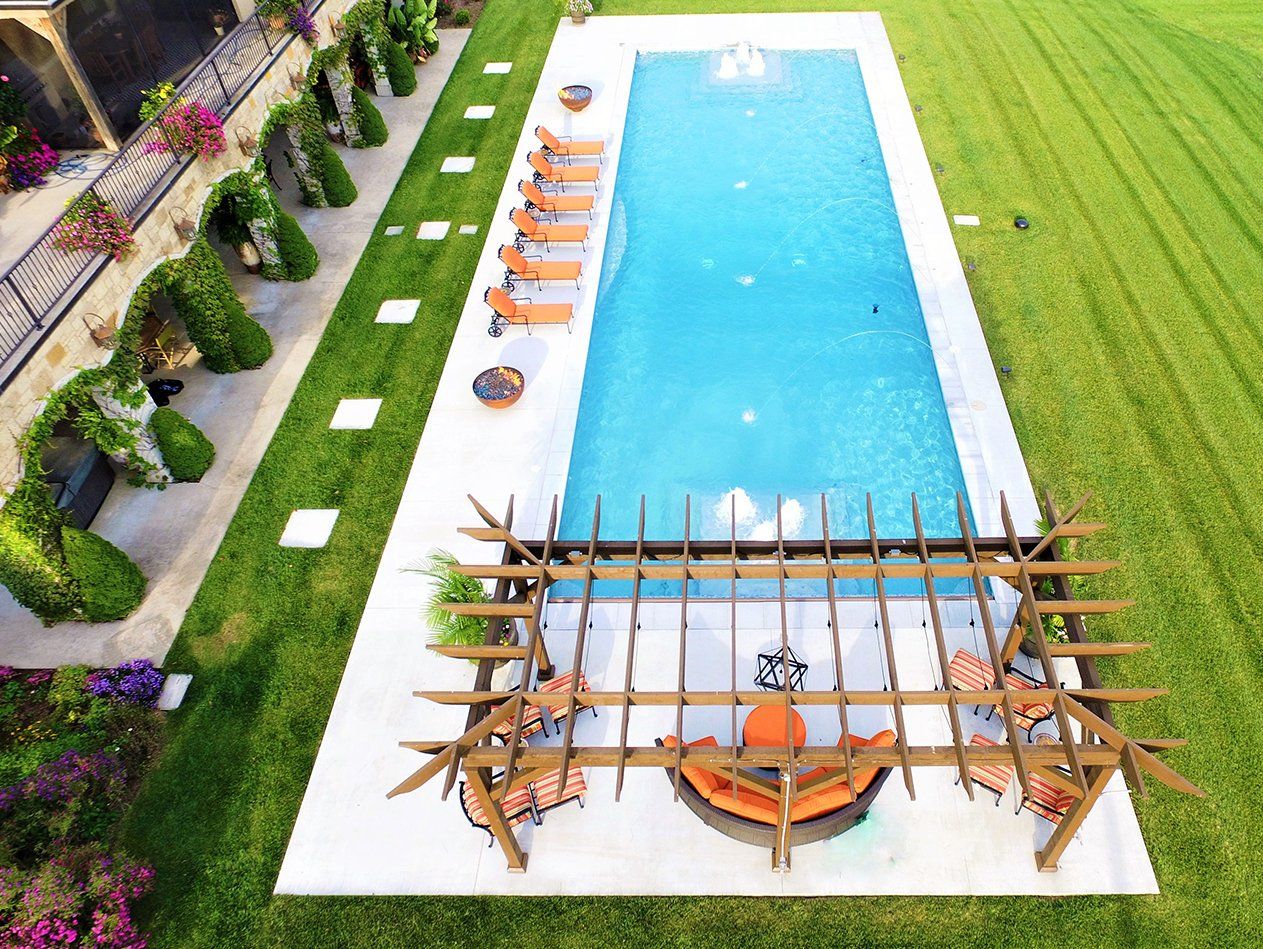An aerial view of a large swimming pool surrounded by lush green grass.