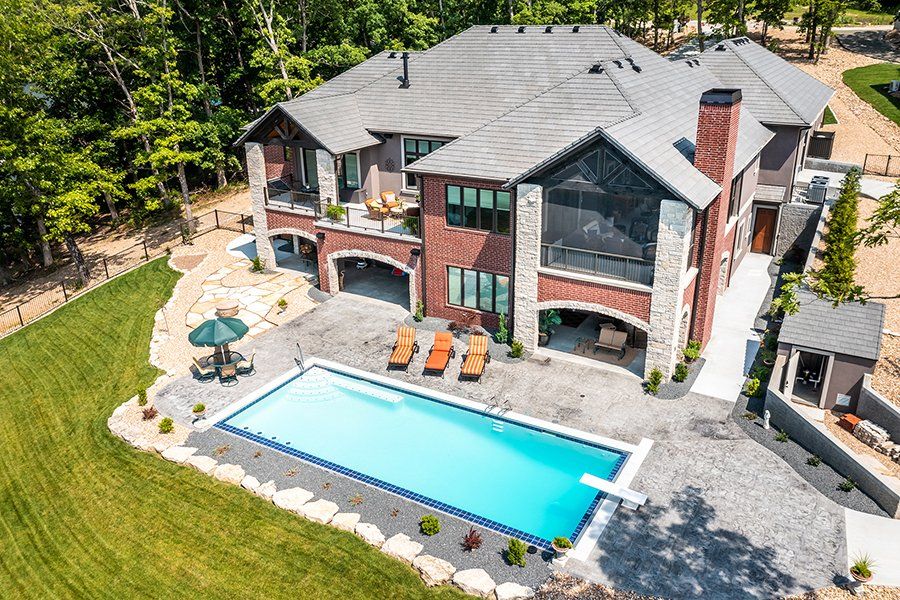 An aerial view of a large house with a large swimming pool in the backyard.