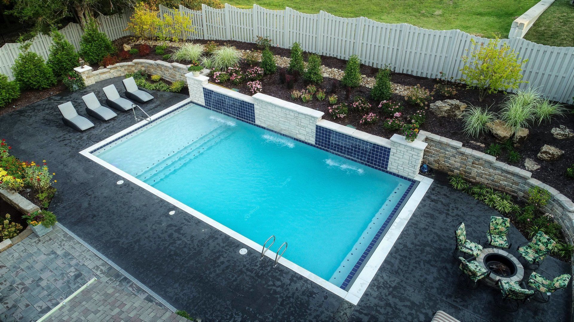 An aerial view of a large swimming pool surrounded by chairs and a fence.