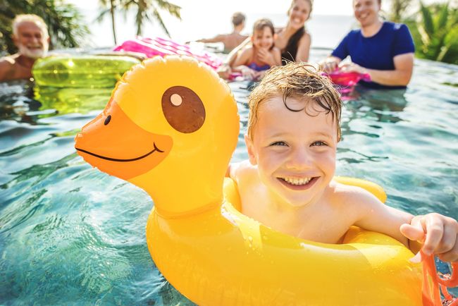 A young boy is swimming in a pool with an inflatable duck.