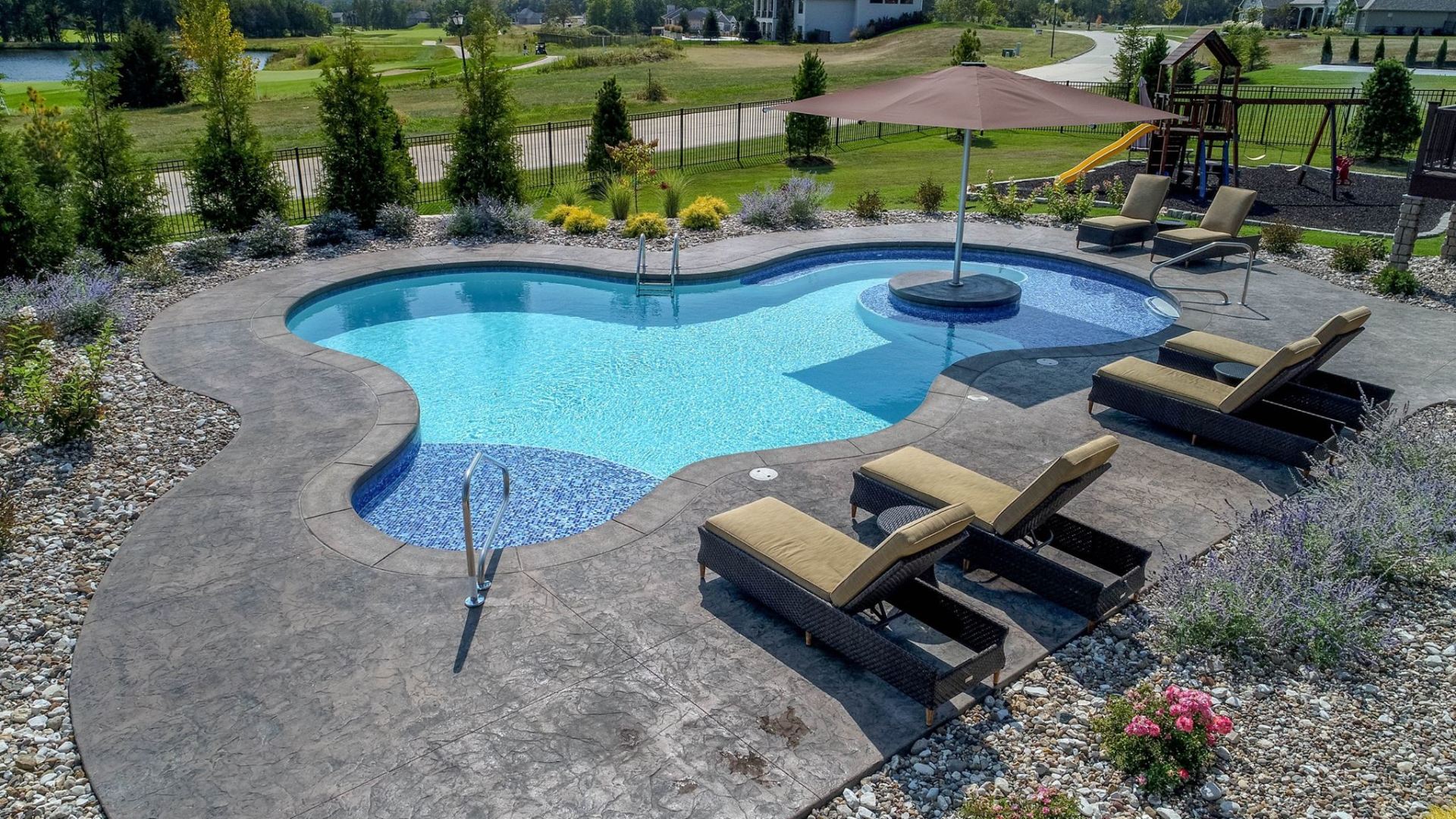 An aerial view of a large swimming pool surrounded by chairs and umbrellas.
