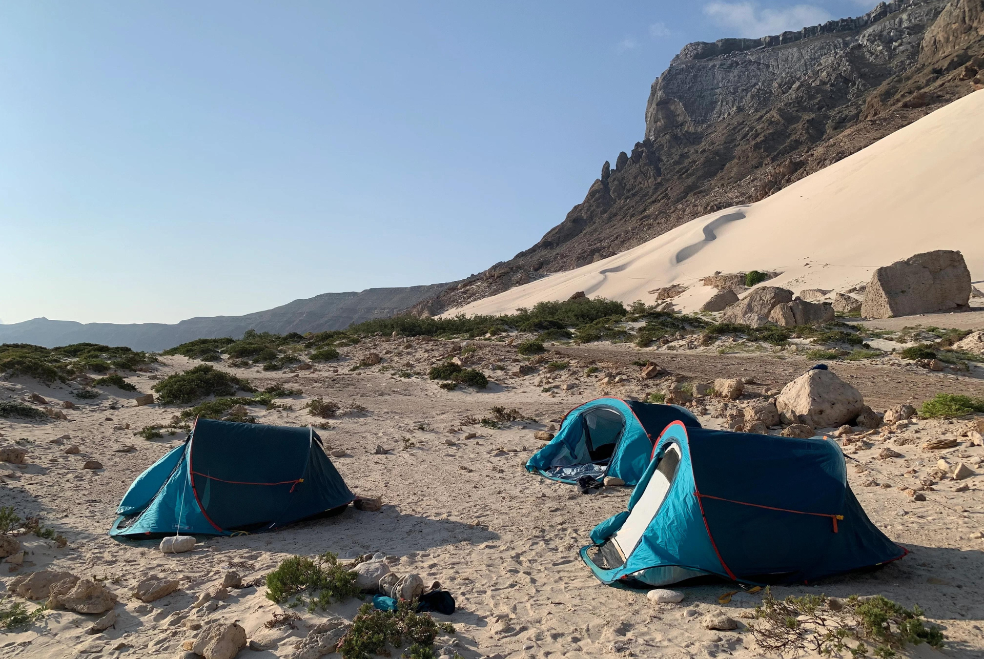 Socotra Island campsite with tents surrounded by mountains and sand dunes.