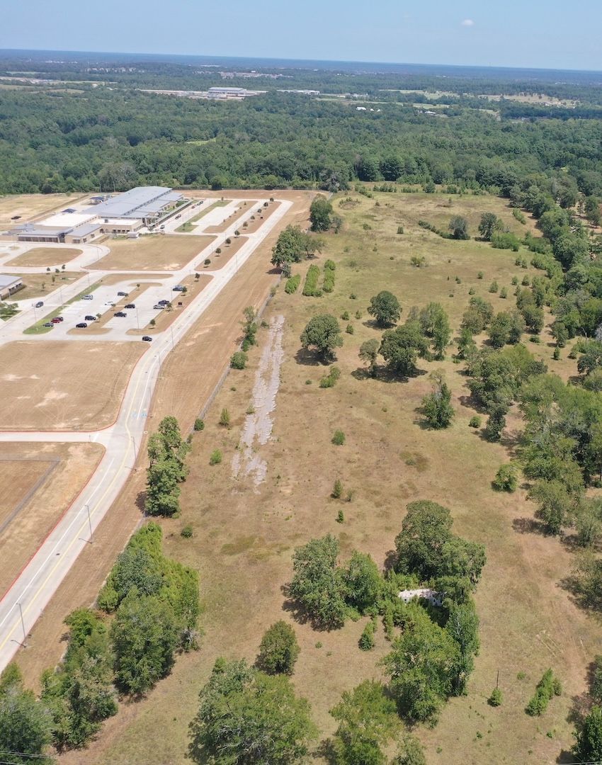 An aerial view of a field with trees and a road