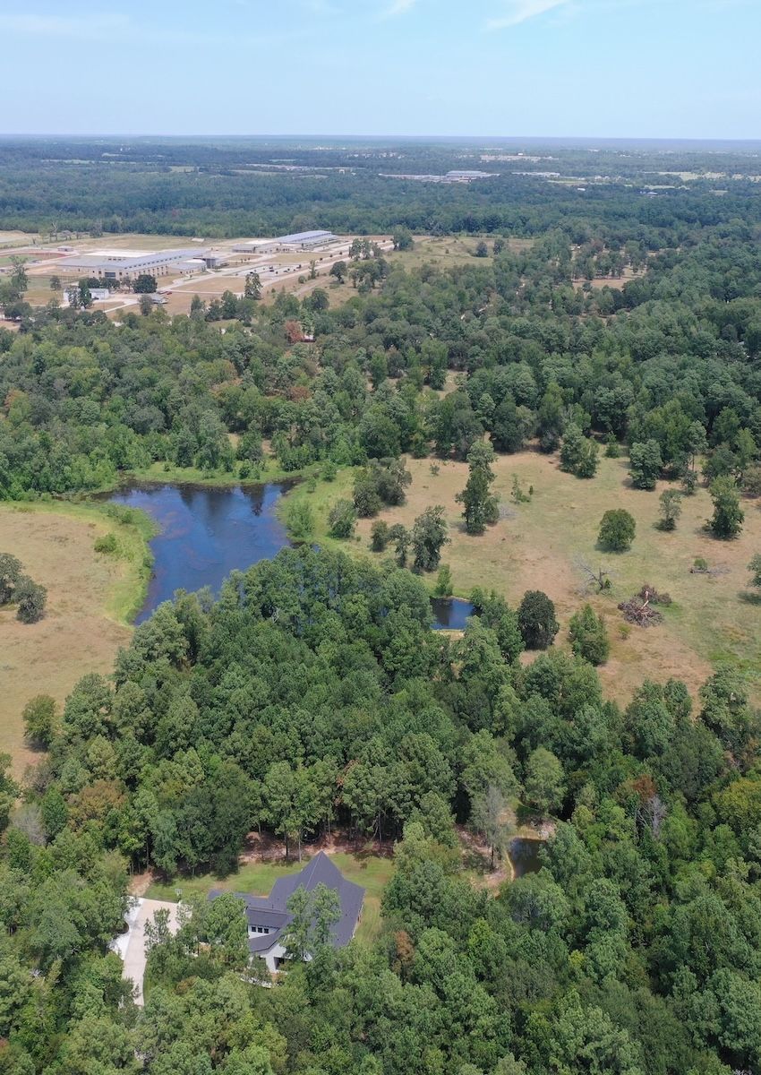 An aerial view of a lush green forest with a lake in the middle.