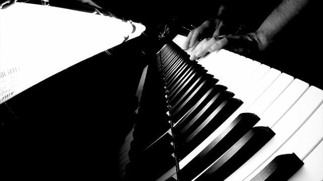 Uma foto em preto e branco de uma pessoa tocando piano