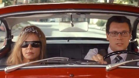 Um homem e uma mulher estão sentados em um carro vermelho.