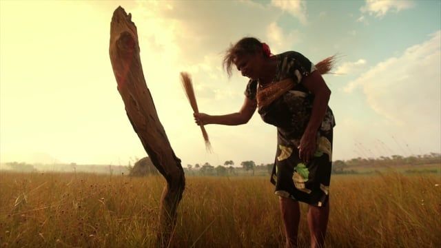 Uma mulher está parada em um campo com uma vara na mão.