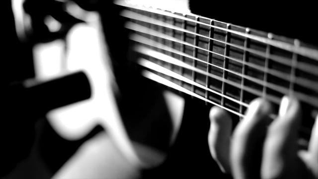 Uma pessoa está tocando violão em uma foto em preto e branco.