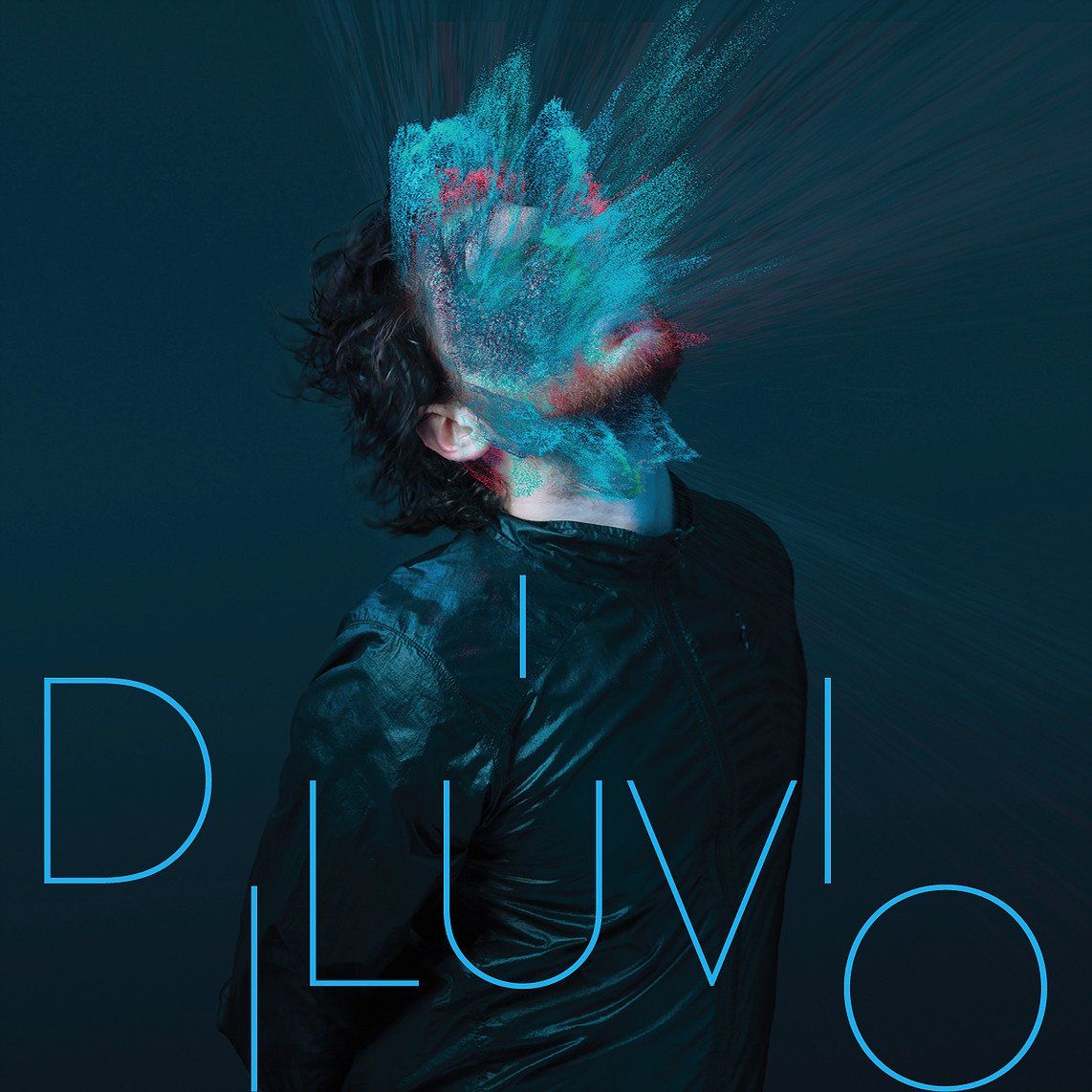 Um homem de jaqueta preta fica em frente a um fundo azul que diz 