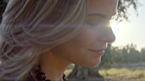 Um close do rosto de uma mulher com o sol brilhando em seus cabelos.