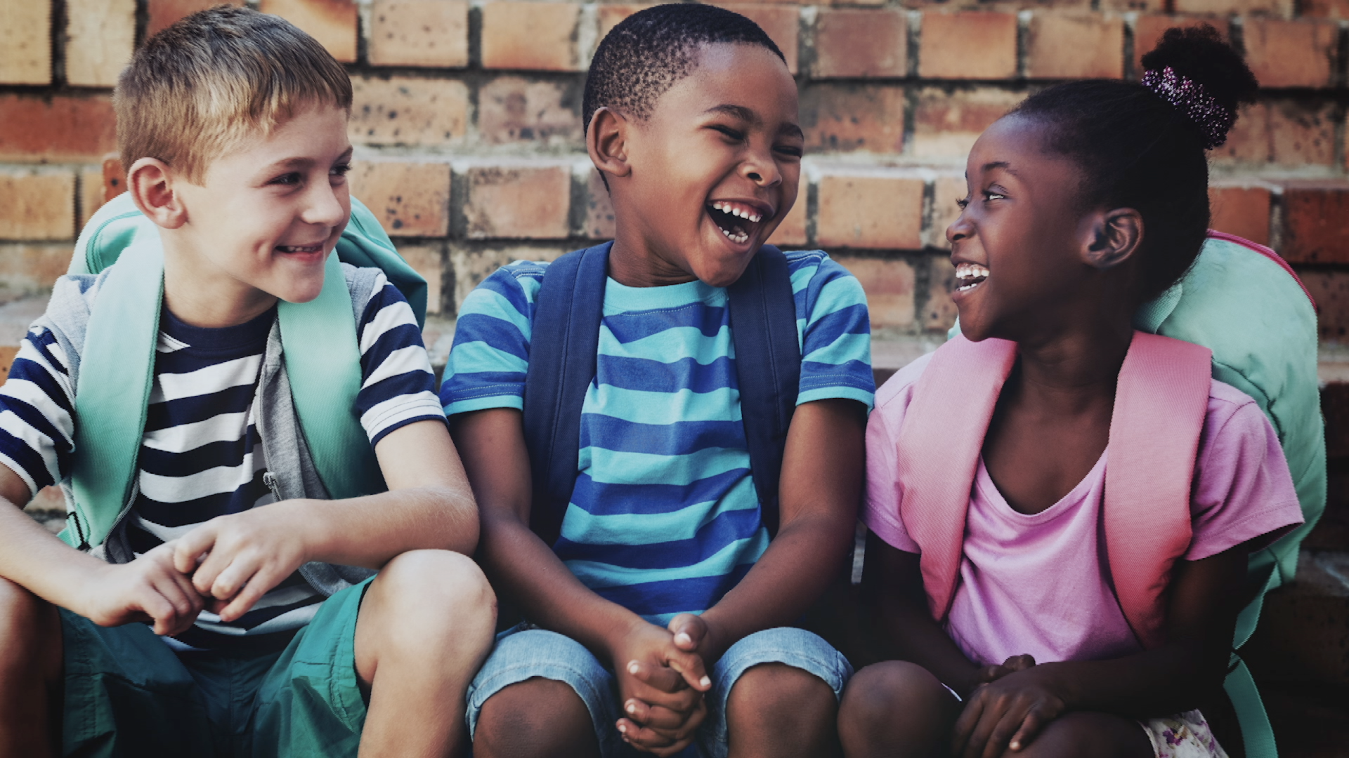 Um grupo de crianças está sentado um ao lado do outro e rindo.