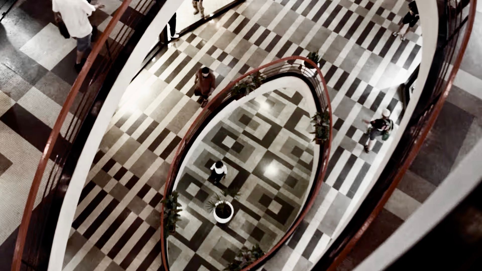 Um grupo de pessoas está diante de um grande espelho no chão xadrez.