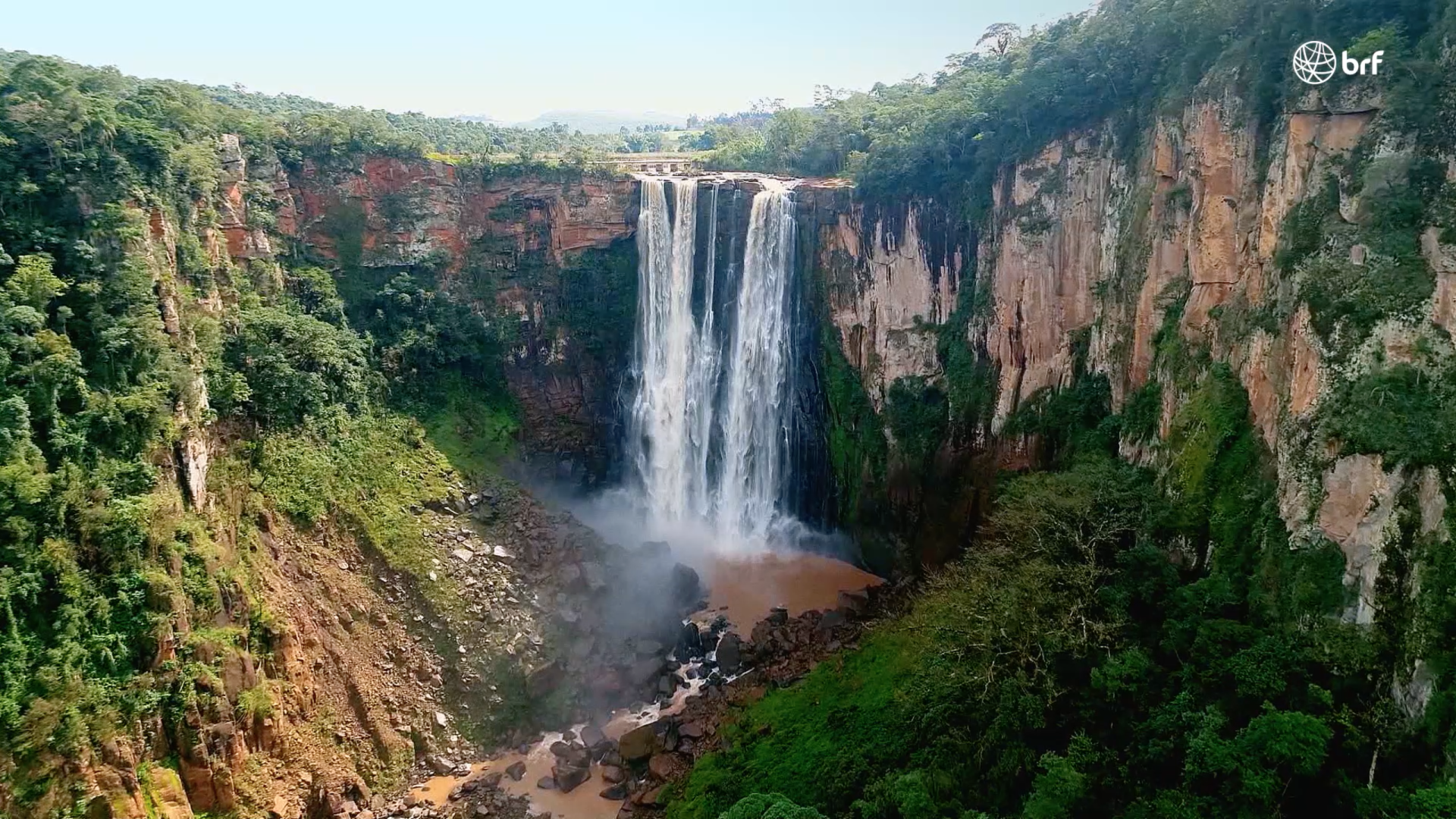 Uma vista aérea de uma cachoeira no meio de uma floresta verdejante.