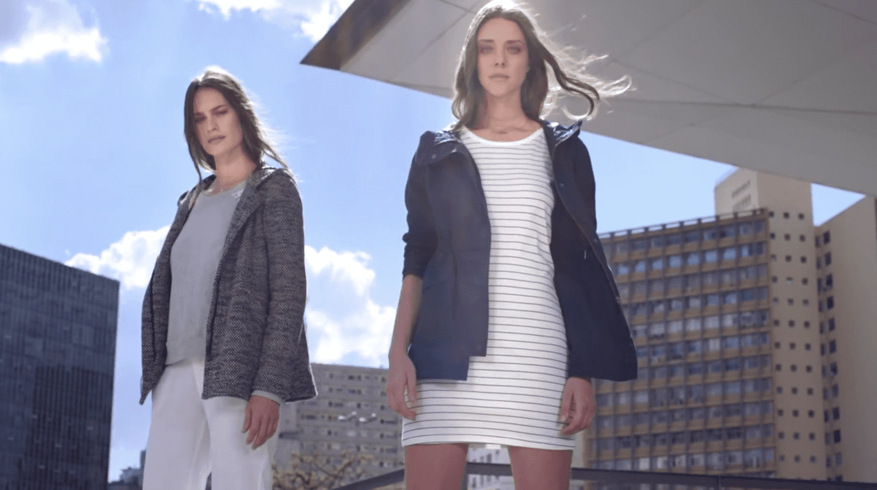 Duas mulheres estão lado a lado em frente a um prédio.