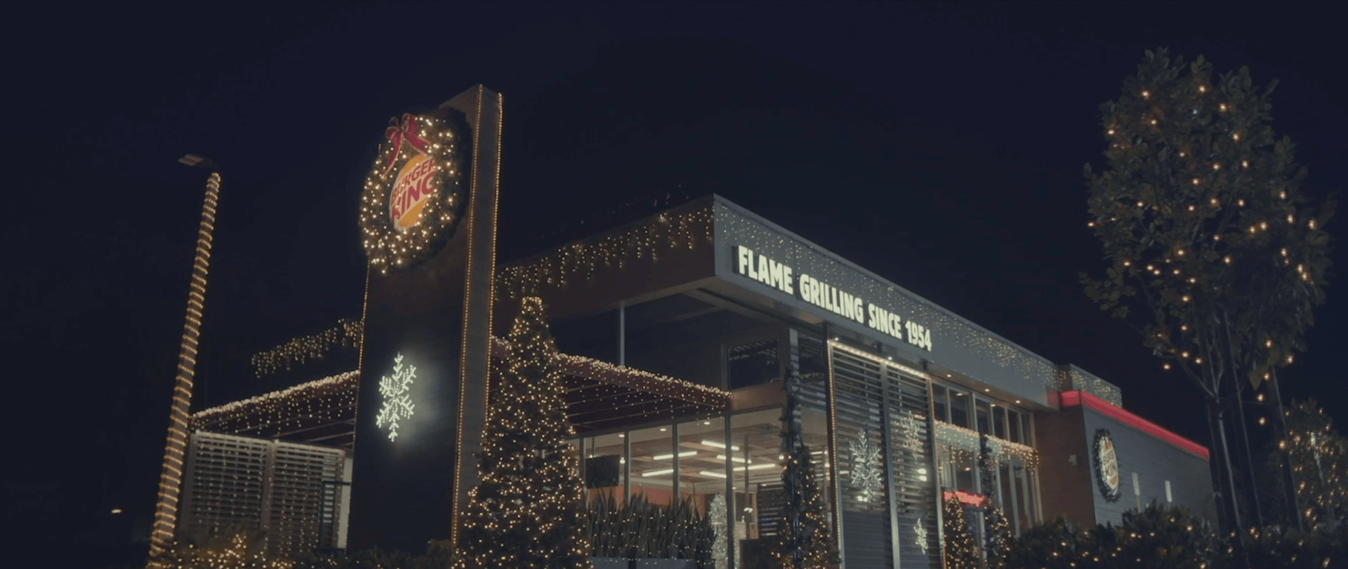 Um grande edifício com luzes de Natal acesas fica iluminado à noite.