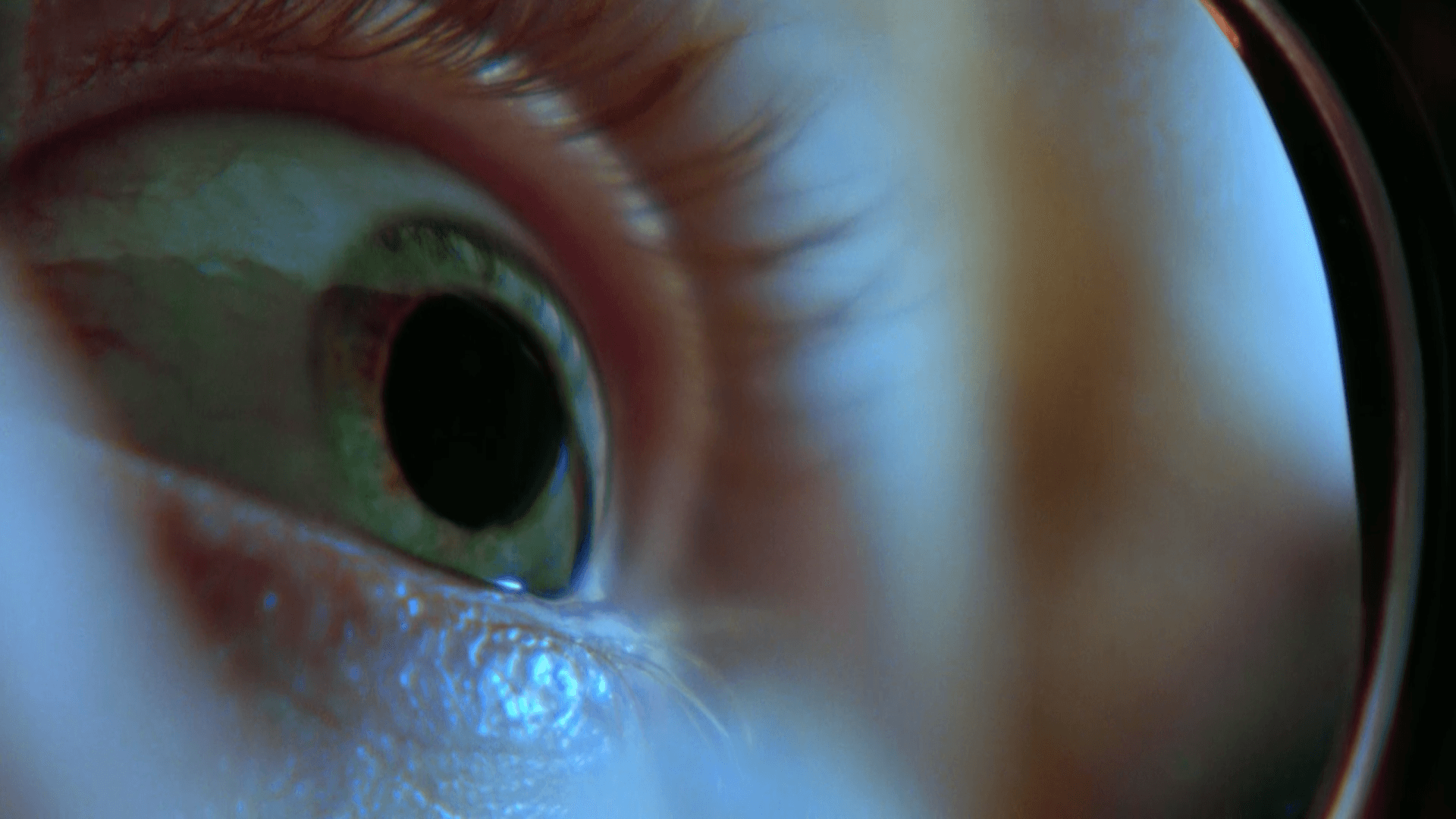 Um close do olho verde de uma pessoa olhando através de uma lupa.