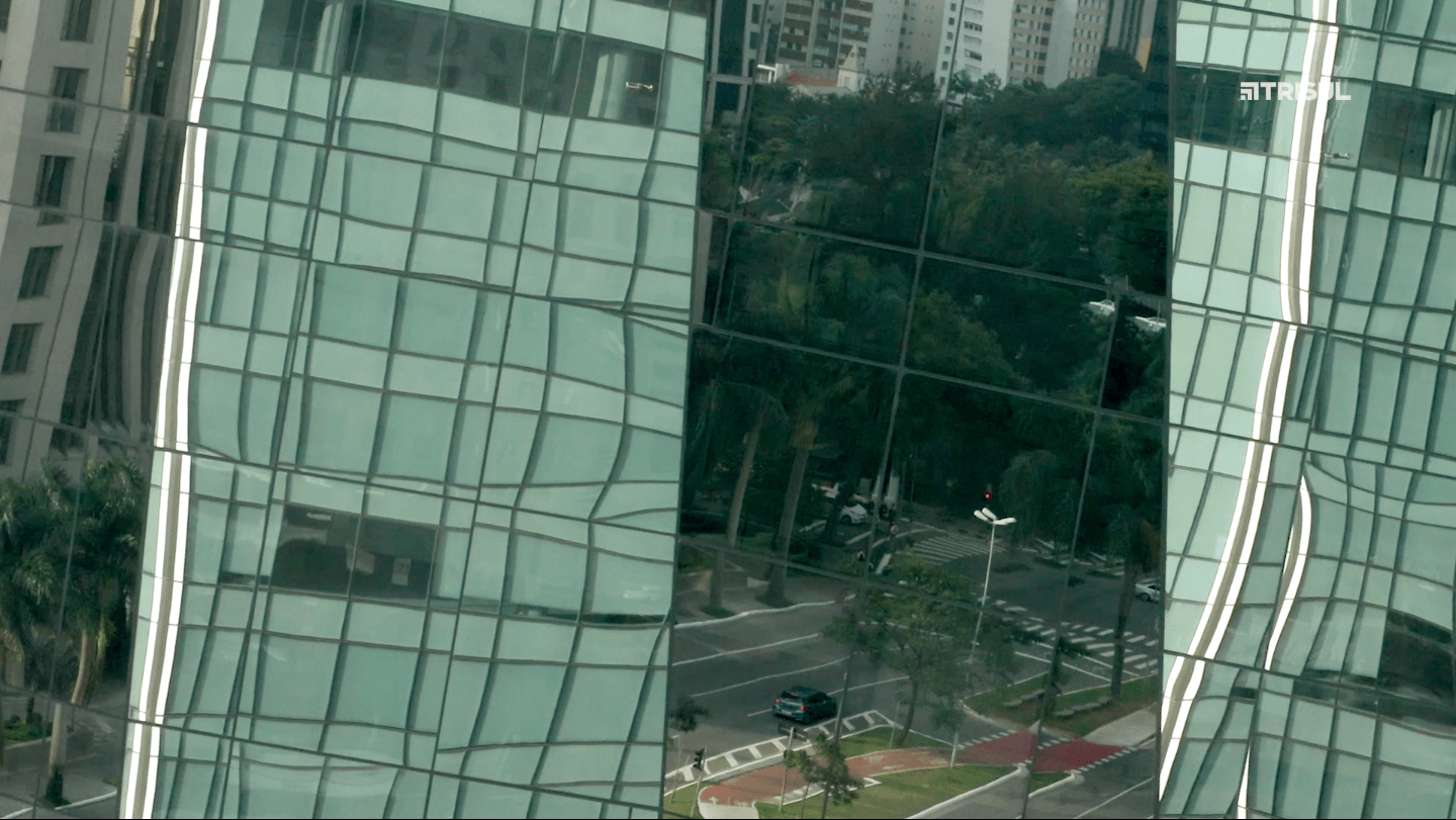 Um grande edifício com muitas janelas reflete-se nas janelas de outro edifício.
