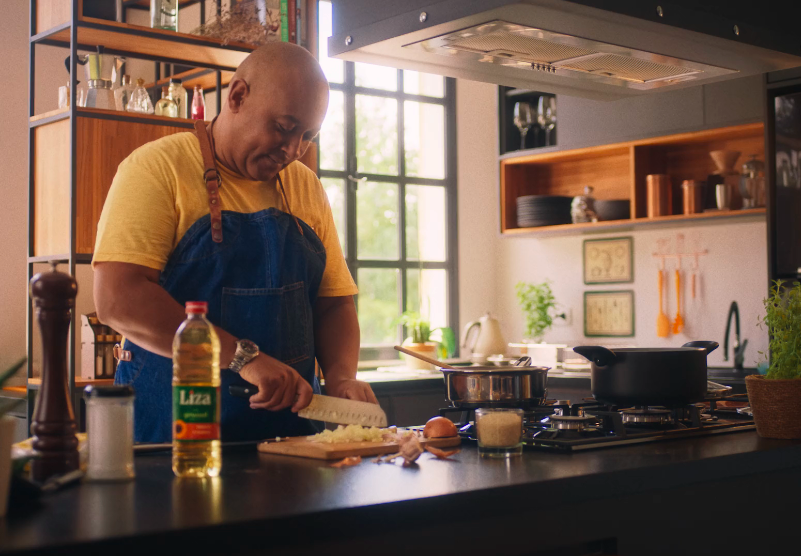 Um homem de avental está cortando legumes em uma cozinha.