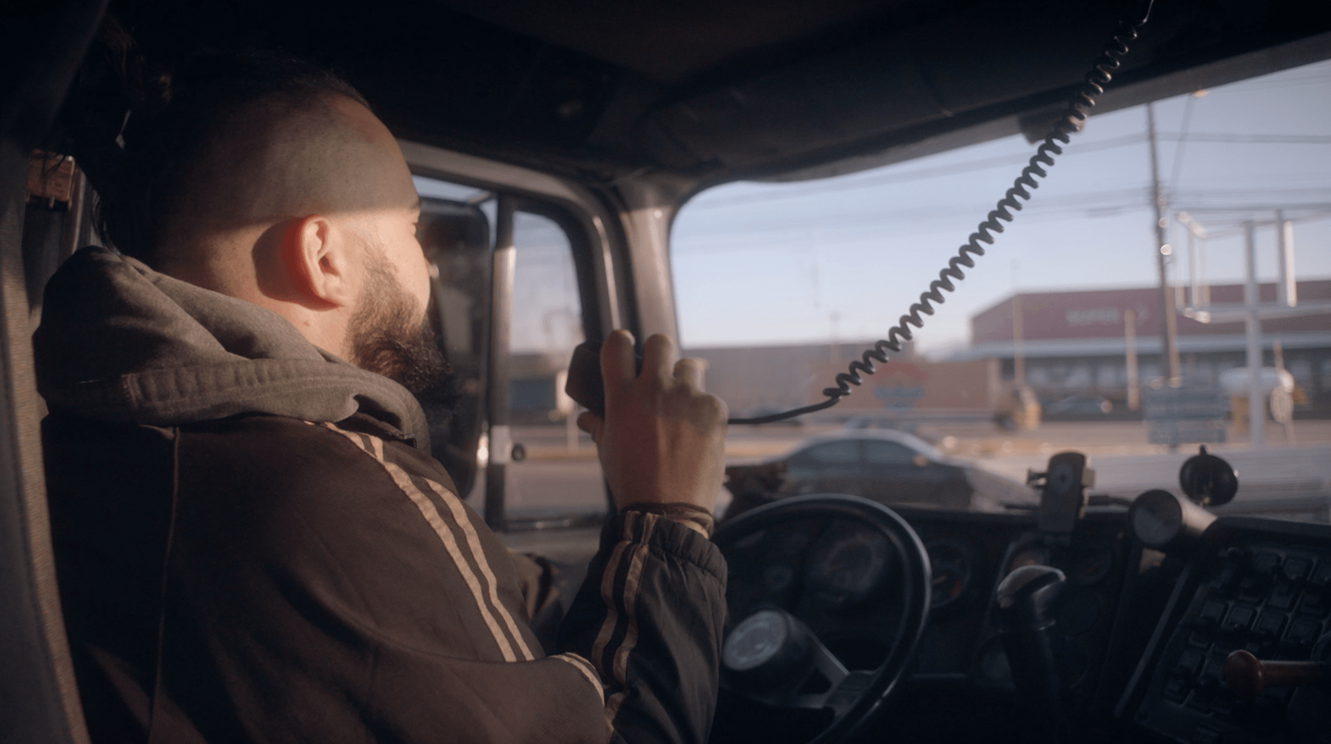 Um homem está dirigindo um caminhão e falando em um walkie talkie.