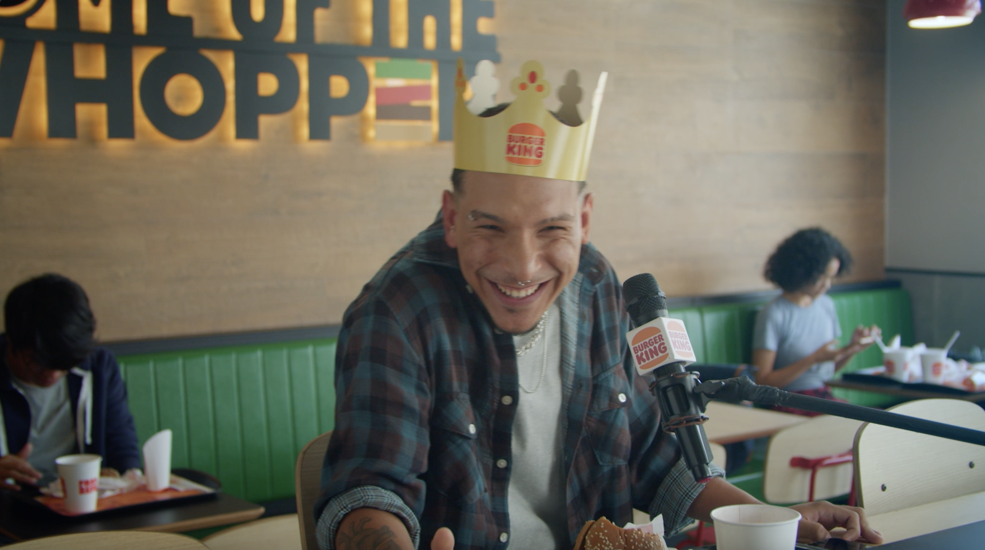Um homem usando uma coroa está sentado à mesa de um restaurante Burger King.