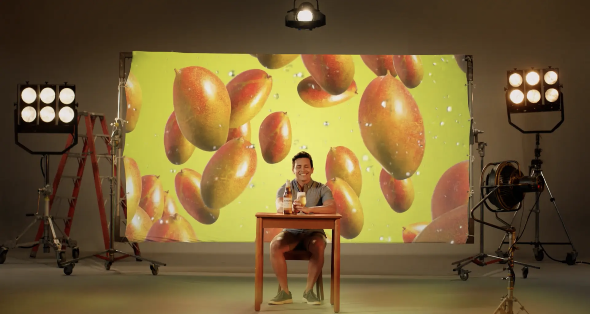 Um homem está sentado a uma mesa em frente a uma grande tela com mangas.