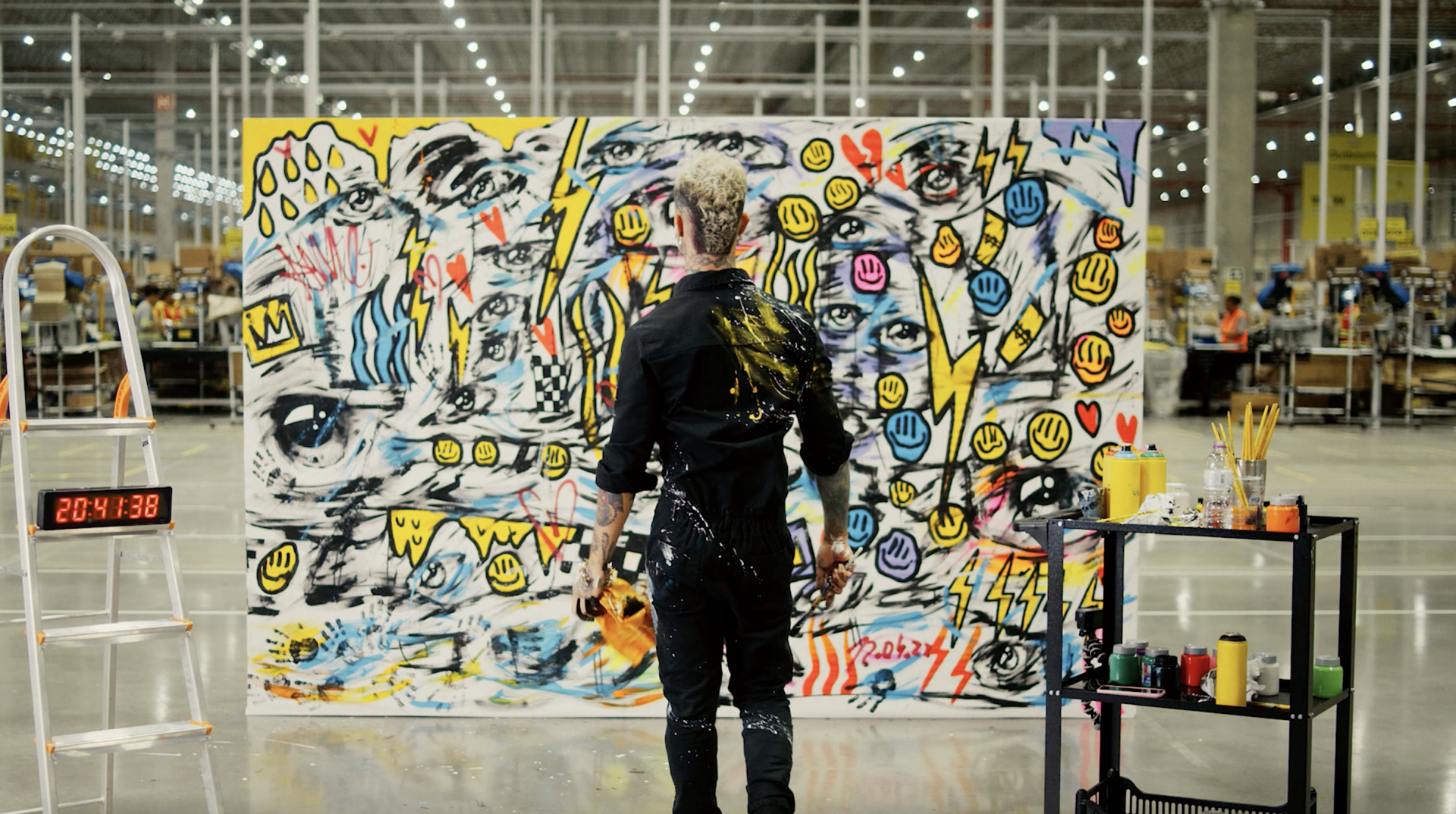 Um homem está diante de uma grande pintura em um armazém.