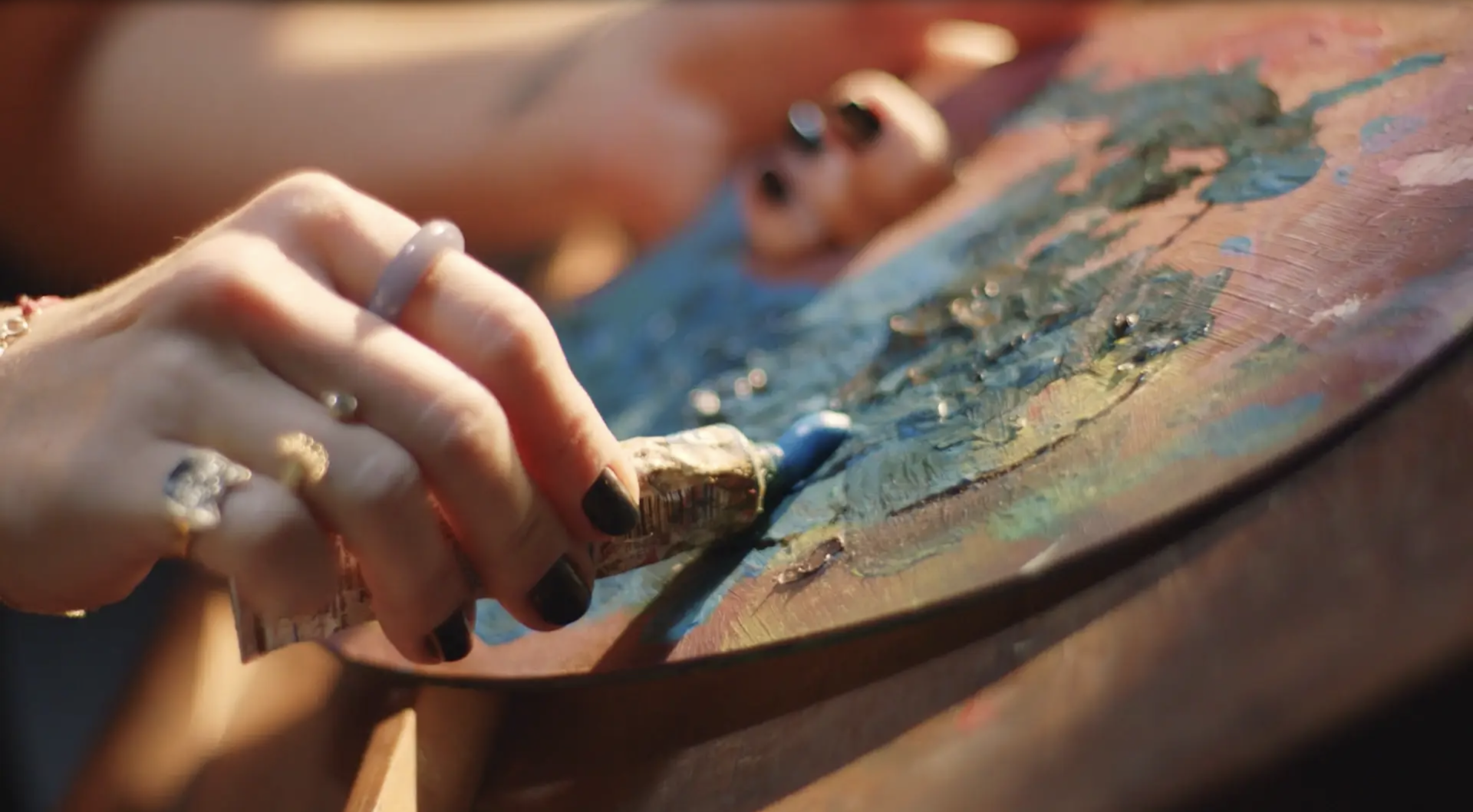 Uma mulher está pintando em uma paleta com um pincel.