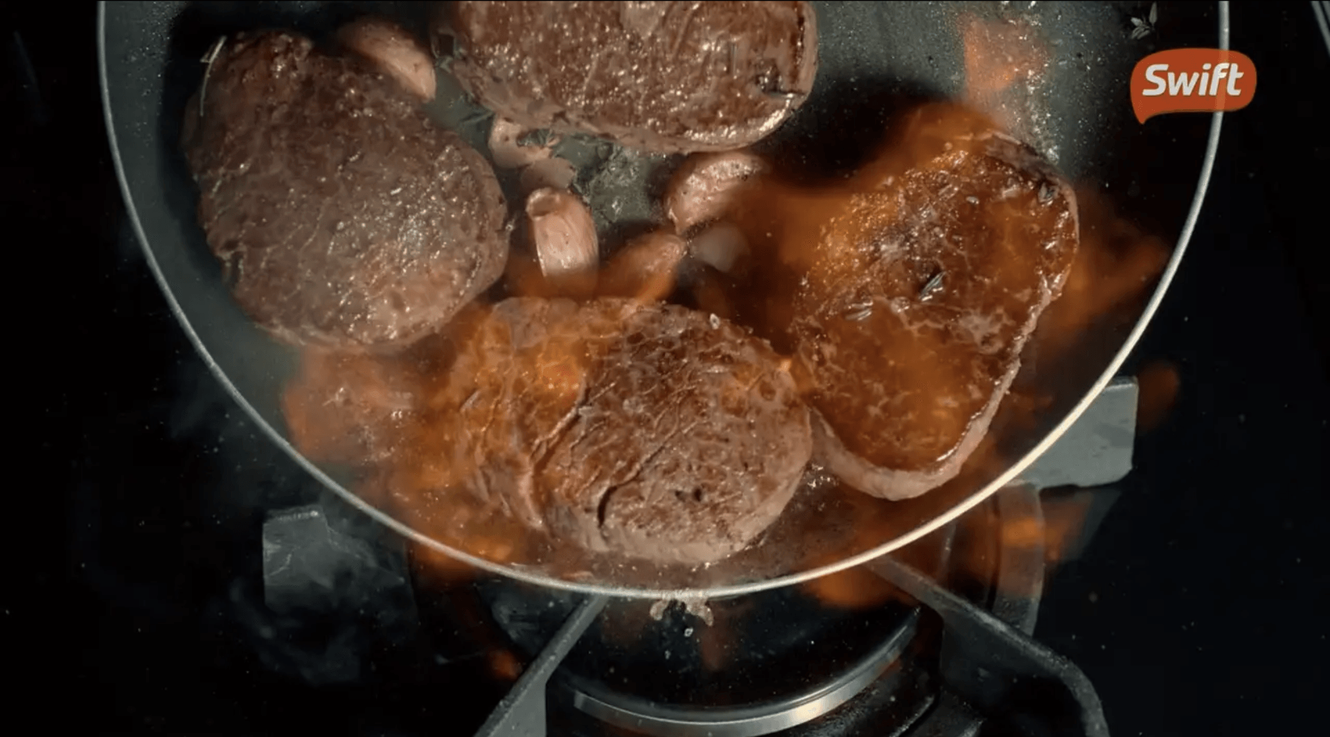 Uma panela cheia de hambúrgueres está cozinhando no fogão.