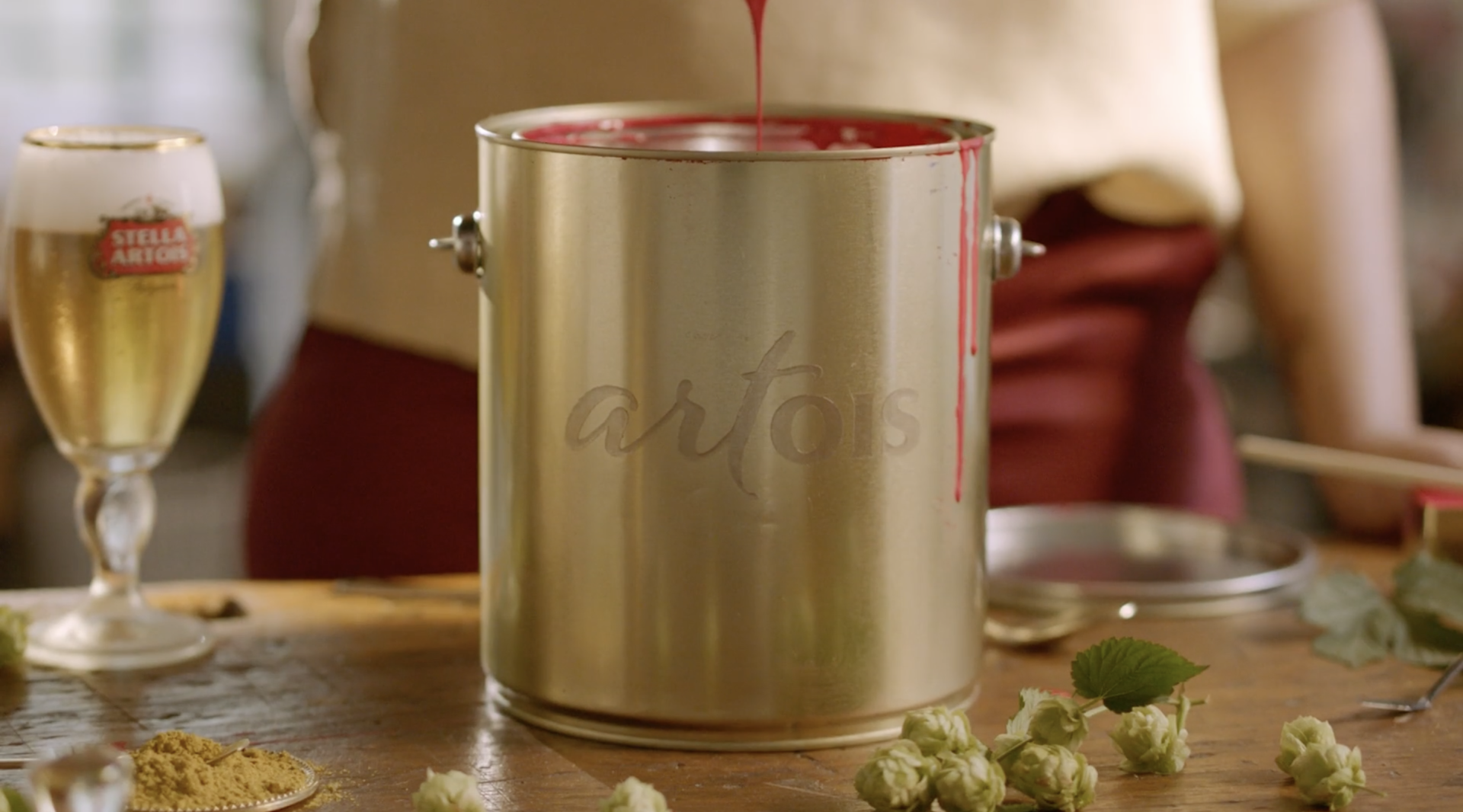 Uma lata de tinta está sobre uma mesa de madeira ao lado de um copo de cerveja.