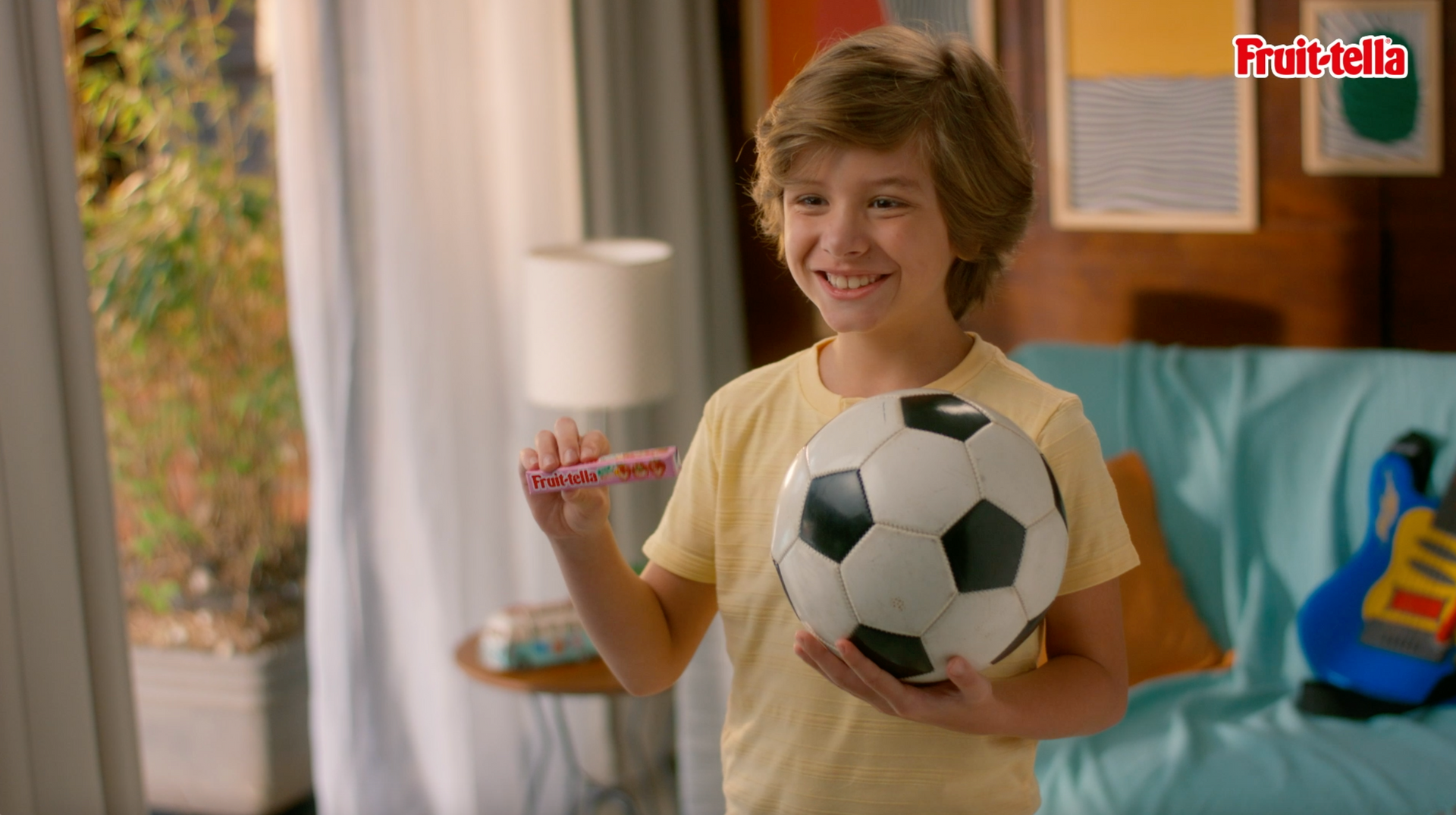 Um menino está segurando uma bola de futebol e um frisbee nas mãos.