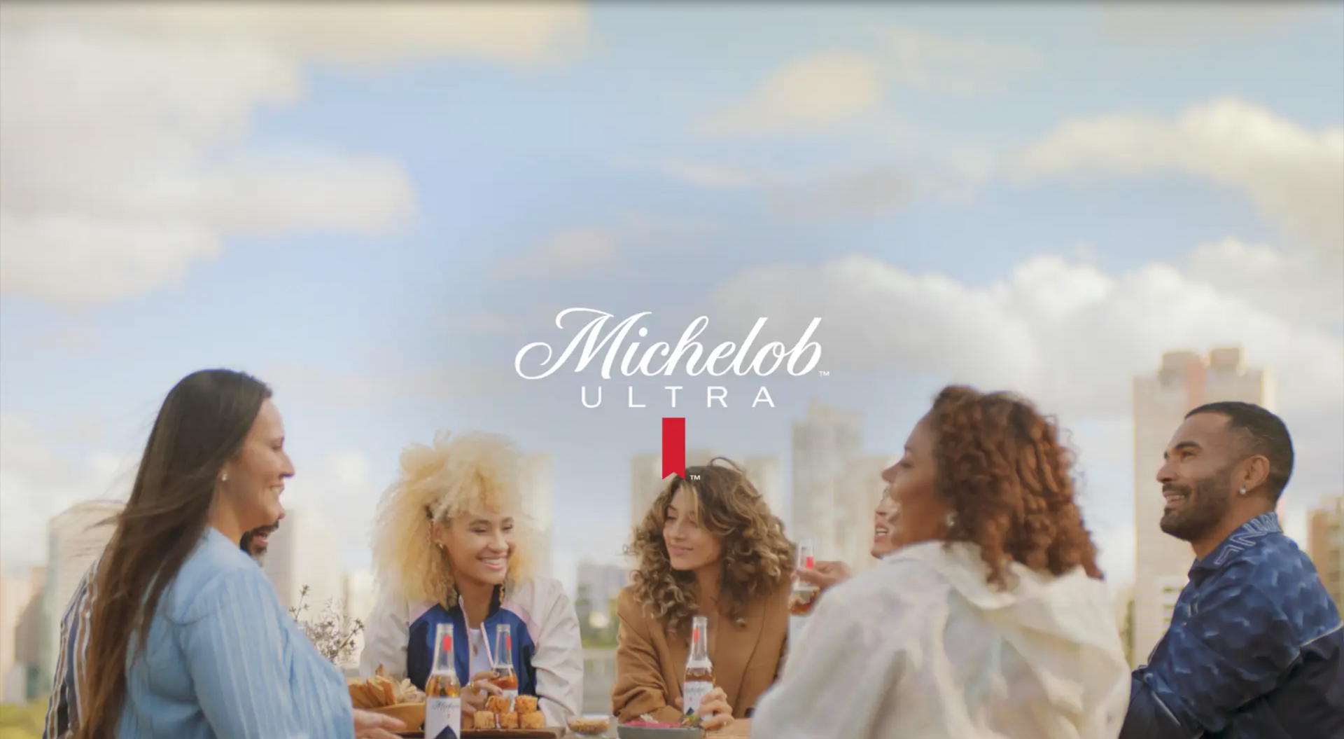 Um grupo de pessoas está sentado em volta de uma mesa bebendo cerveja.