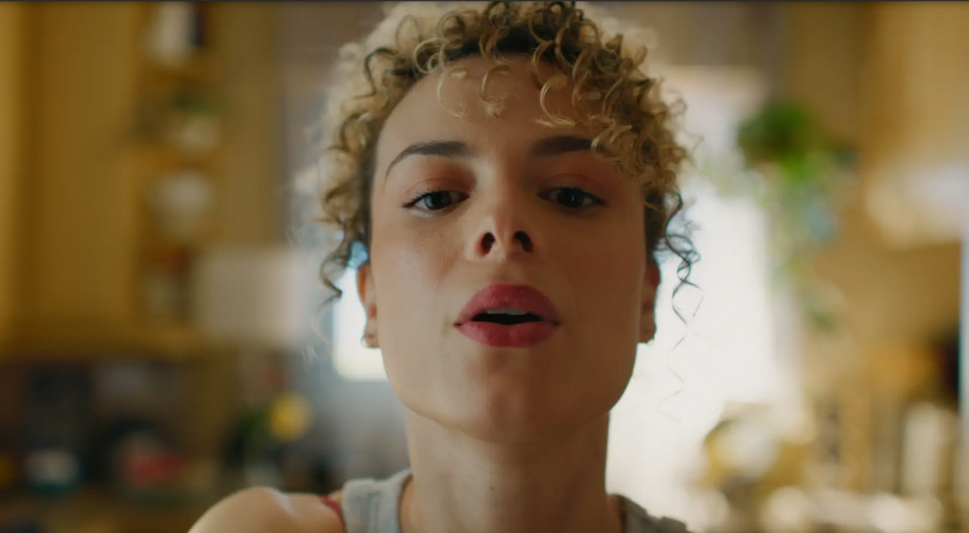 Um close de uma mulher com cabelos cacheados fazendo uma careta engraçada.