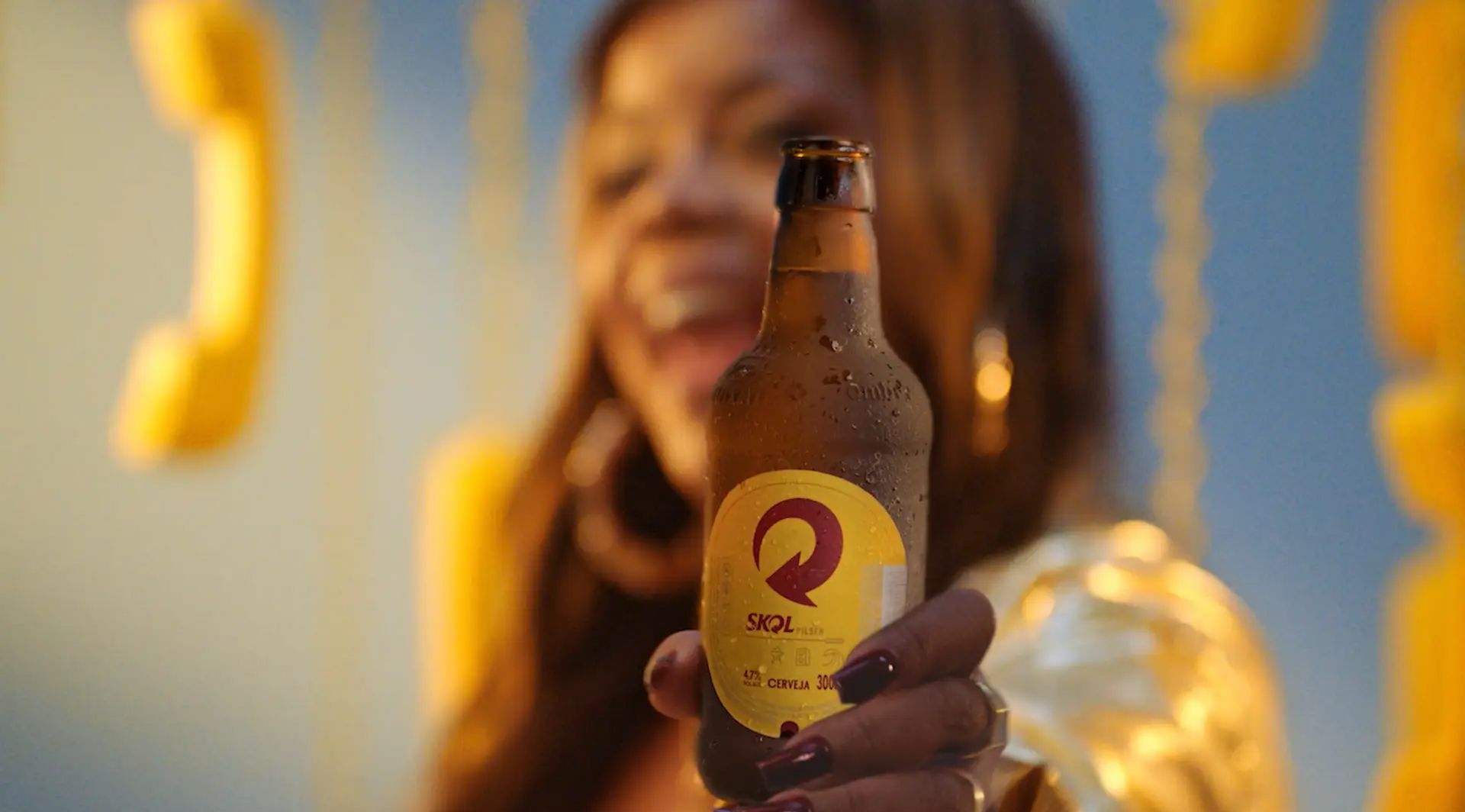 Uma mulher está segurando uma garrafa de cerveja na mão.