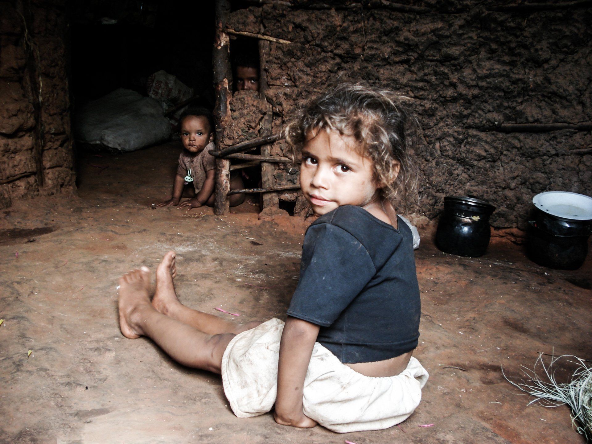 Uma menina está sentada no chão olhando para a câmera