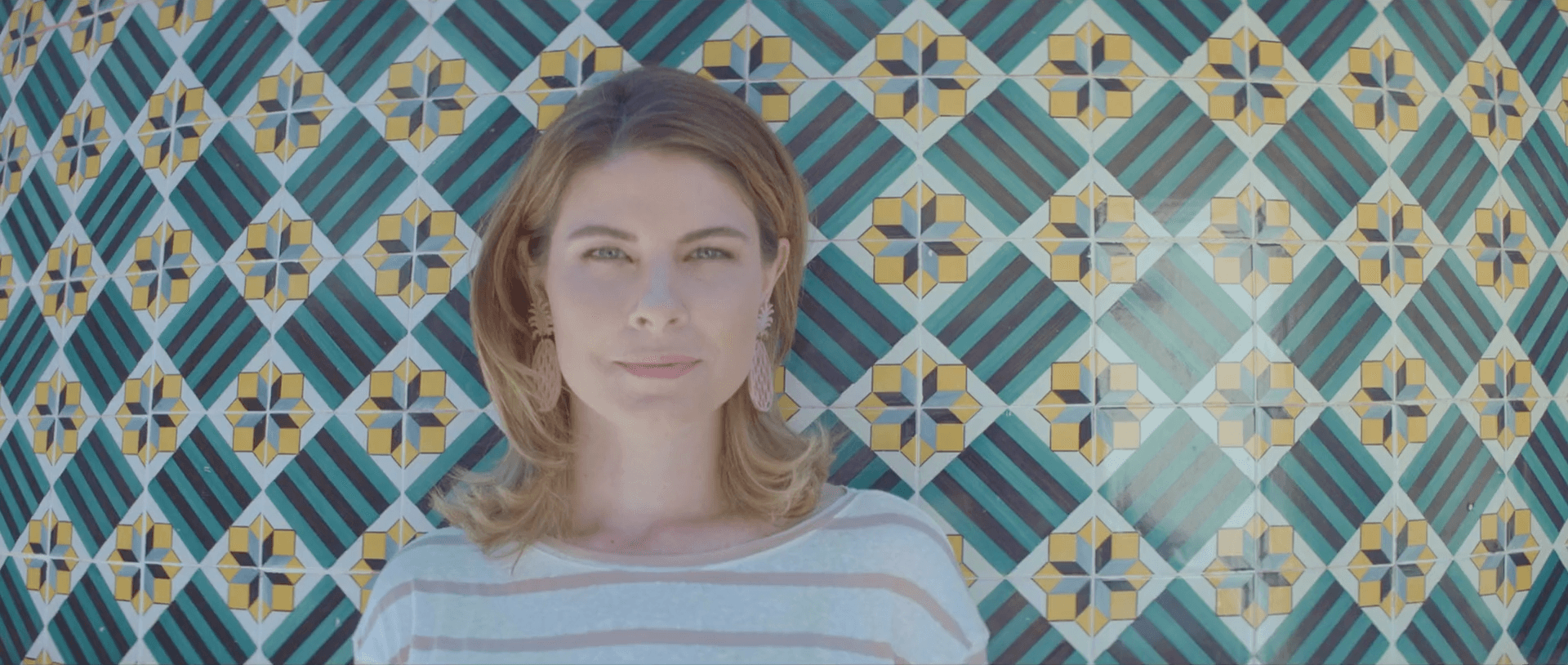 Uma mulher está parada em frente a uma parede de azulejos.