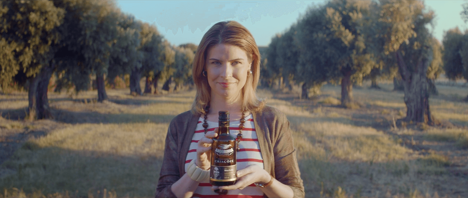 Uma mulher está segurando uma garrafa de cerveja em um campo.