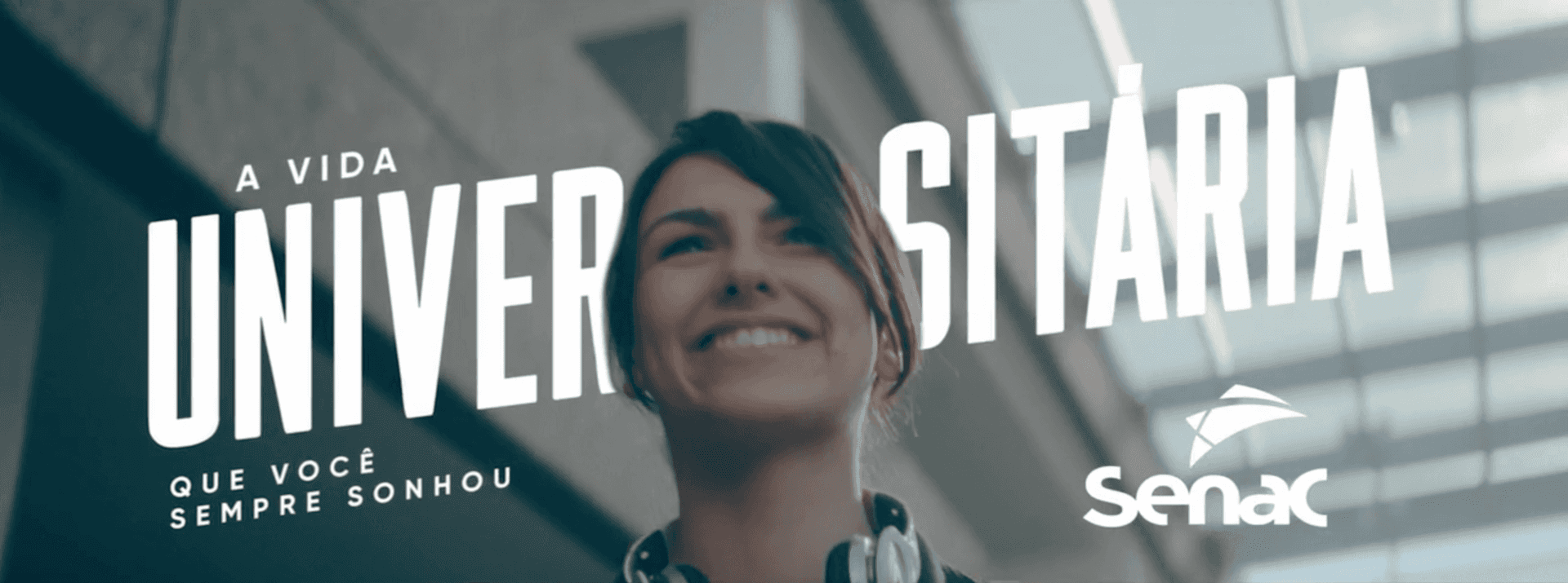 Uma mulher está sorrindo na frente de uma placa que diz universidade