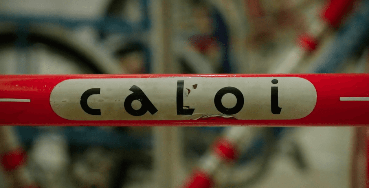 Um close de um quadro de bicicleta vermelho e branco com a palavra caloi.