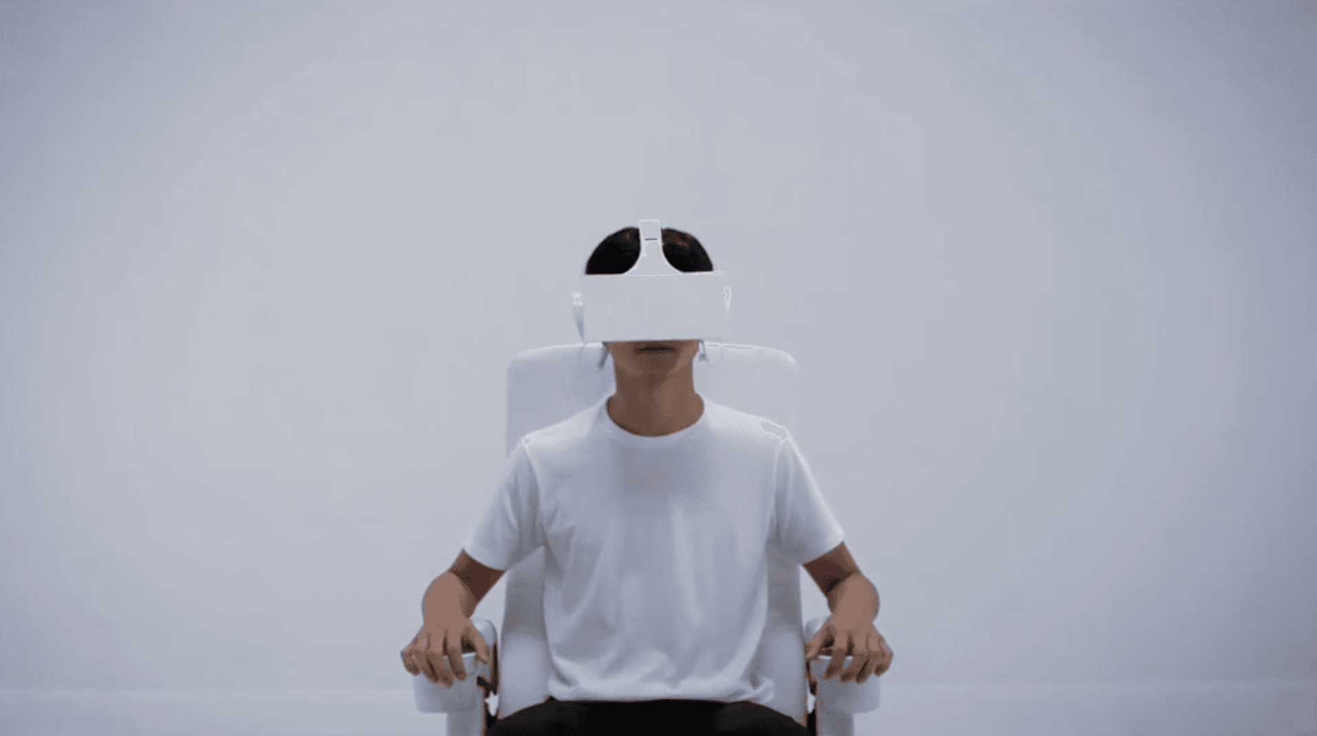 Um homem está sentado em uma cadeira usando um fone de ouvido de realidade virtual.